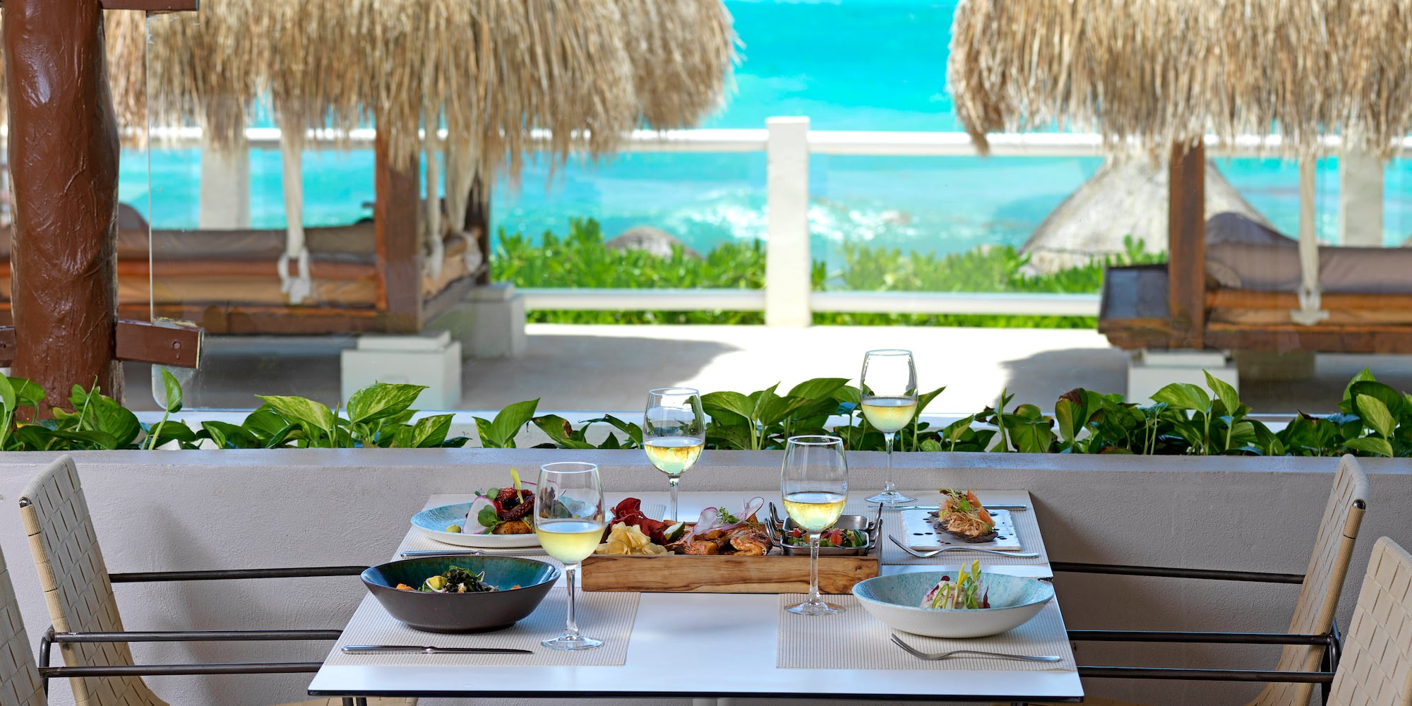 a table with food on it and a table with chairs and straw umbrellas