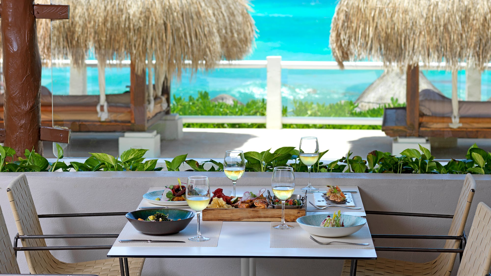 a table with food on it and a table with chairs and straw umbrellas