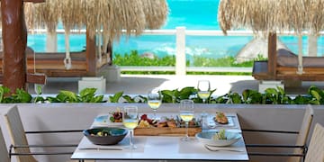 a table with food on it and a table with chairs and straw umbrellas