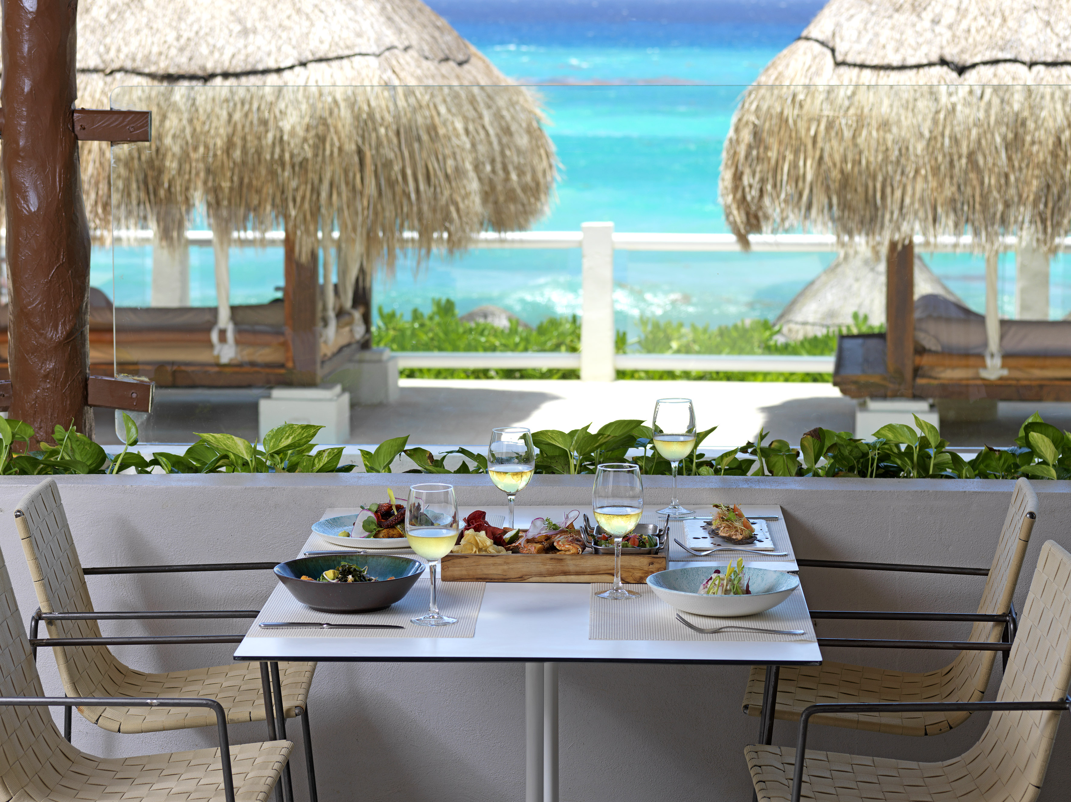 a table with food on it and a table with chairs and straw umbrellas