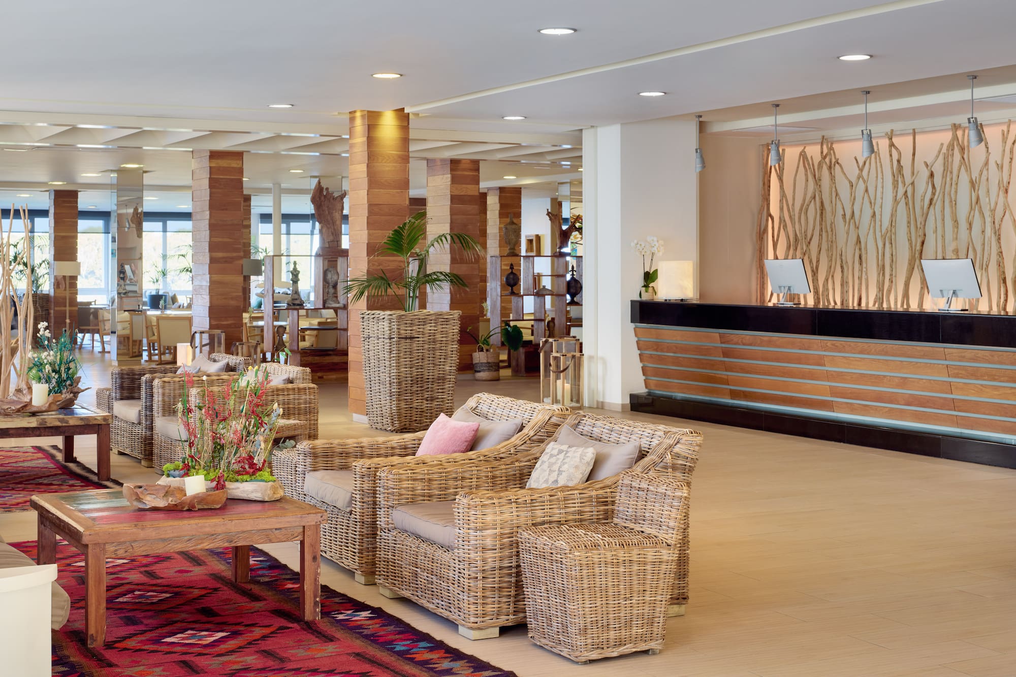 Hotel lobby with rattan furniture, wooden reception, and natural decor.