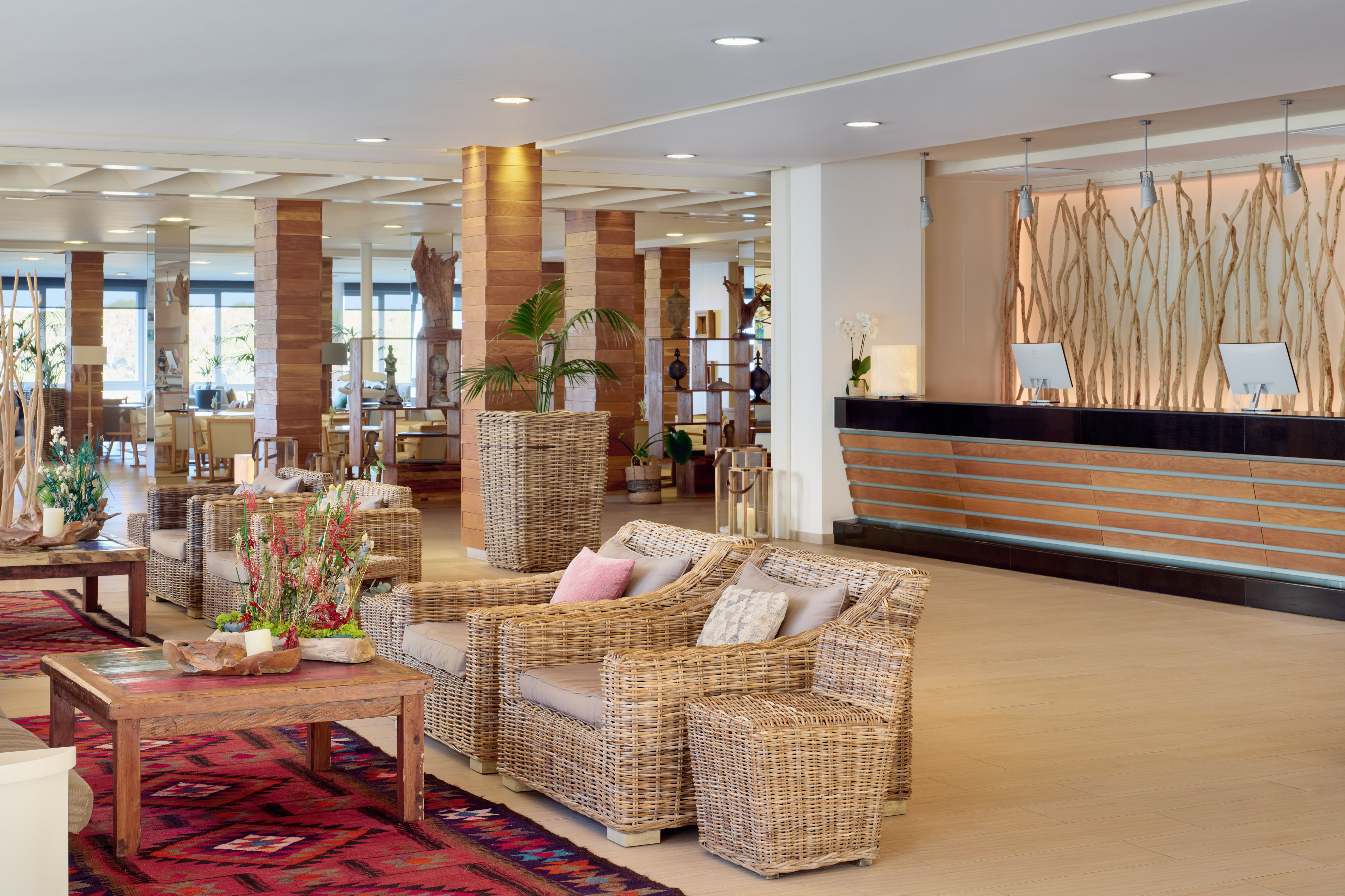 Hotel lobby with rattan furniture, wooden reception, and natural decor.