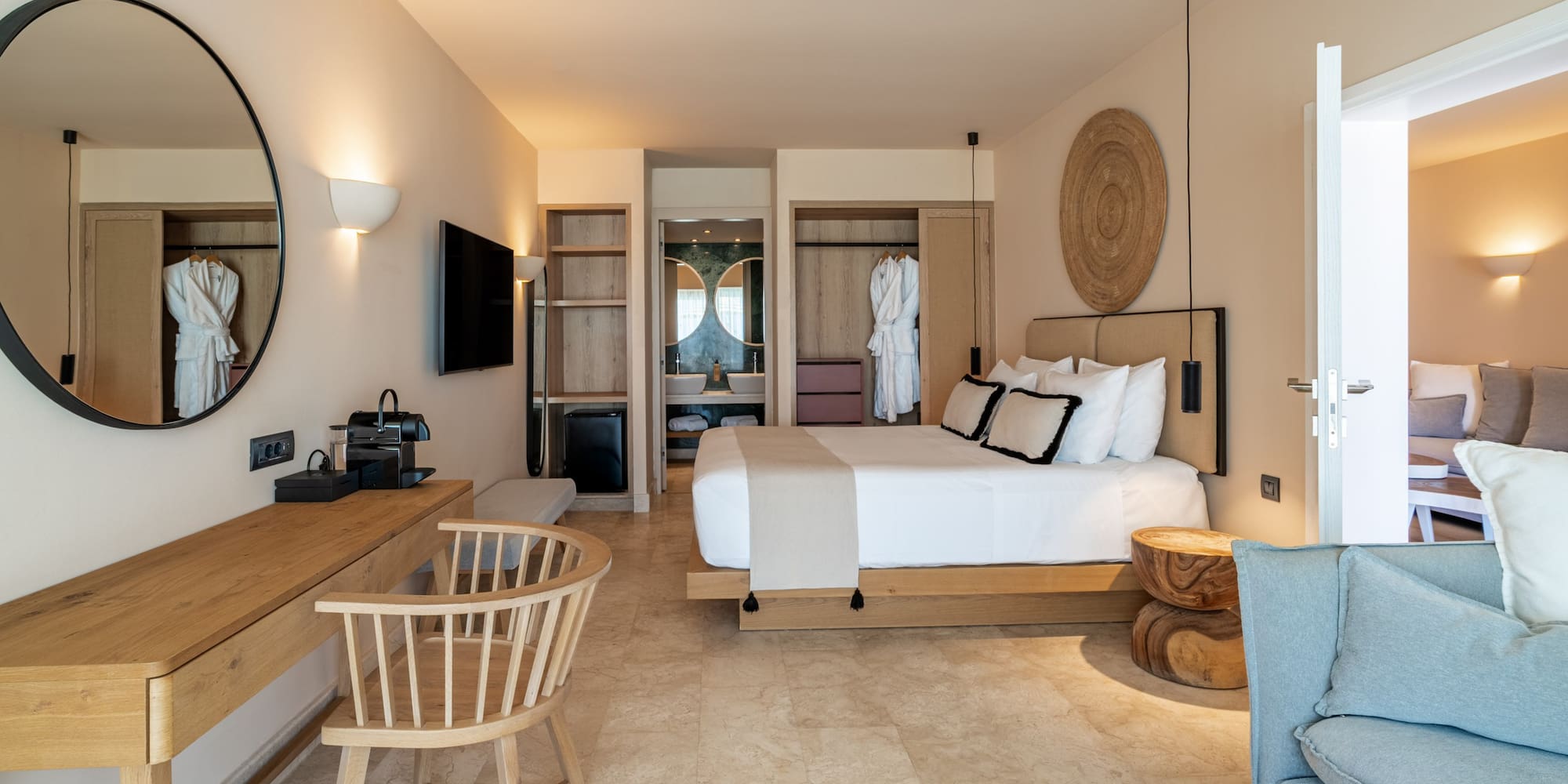 Modern hotel bedroom with white bed, wood furniture, and beige tiled floor.