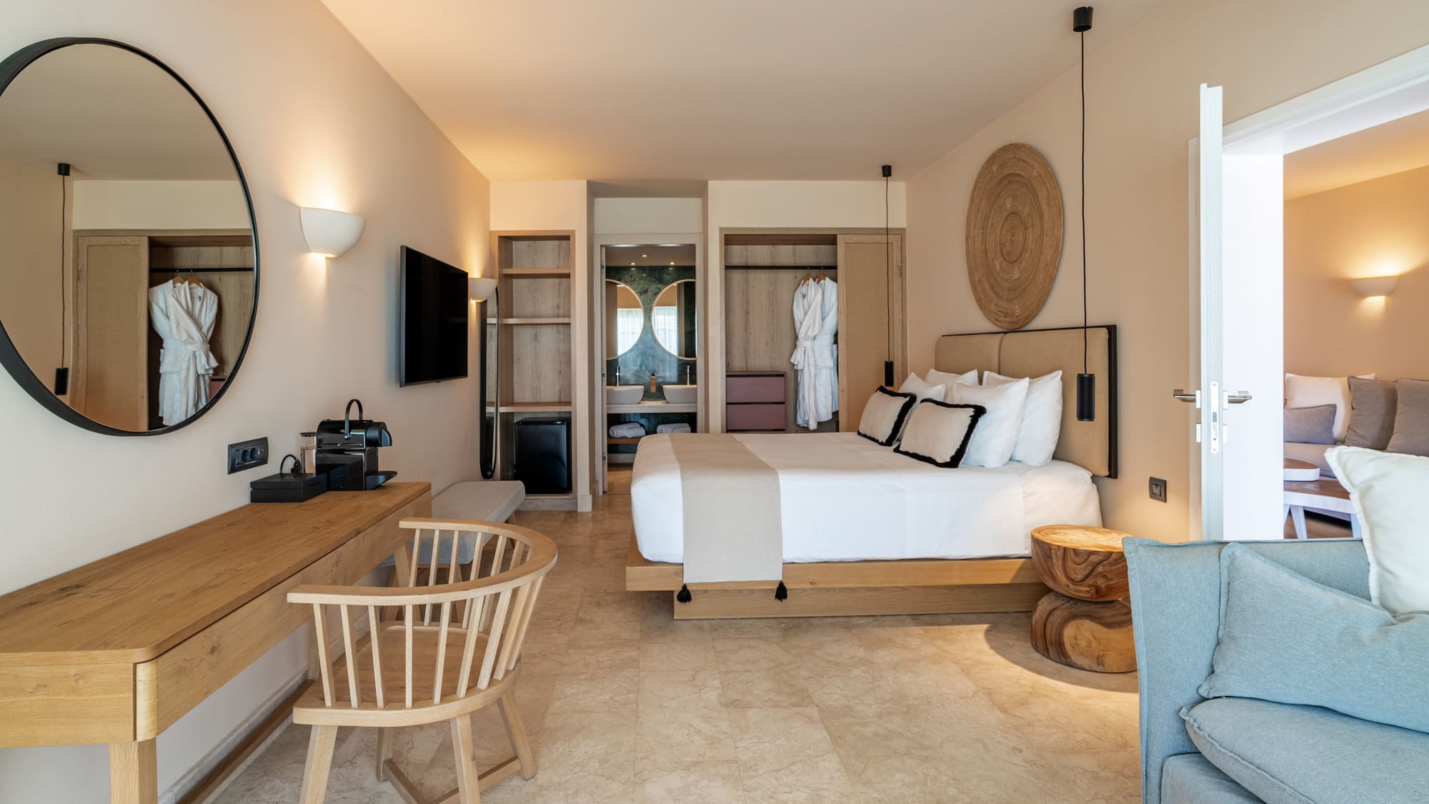 Modern hotel bedroom with white bed, wood furniture, and beige tiled floor.