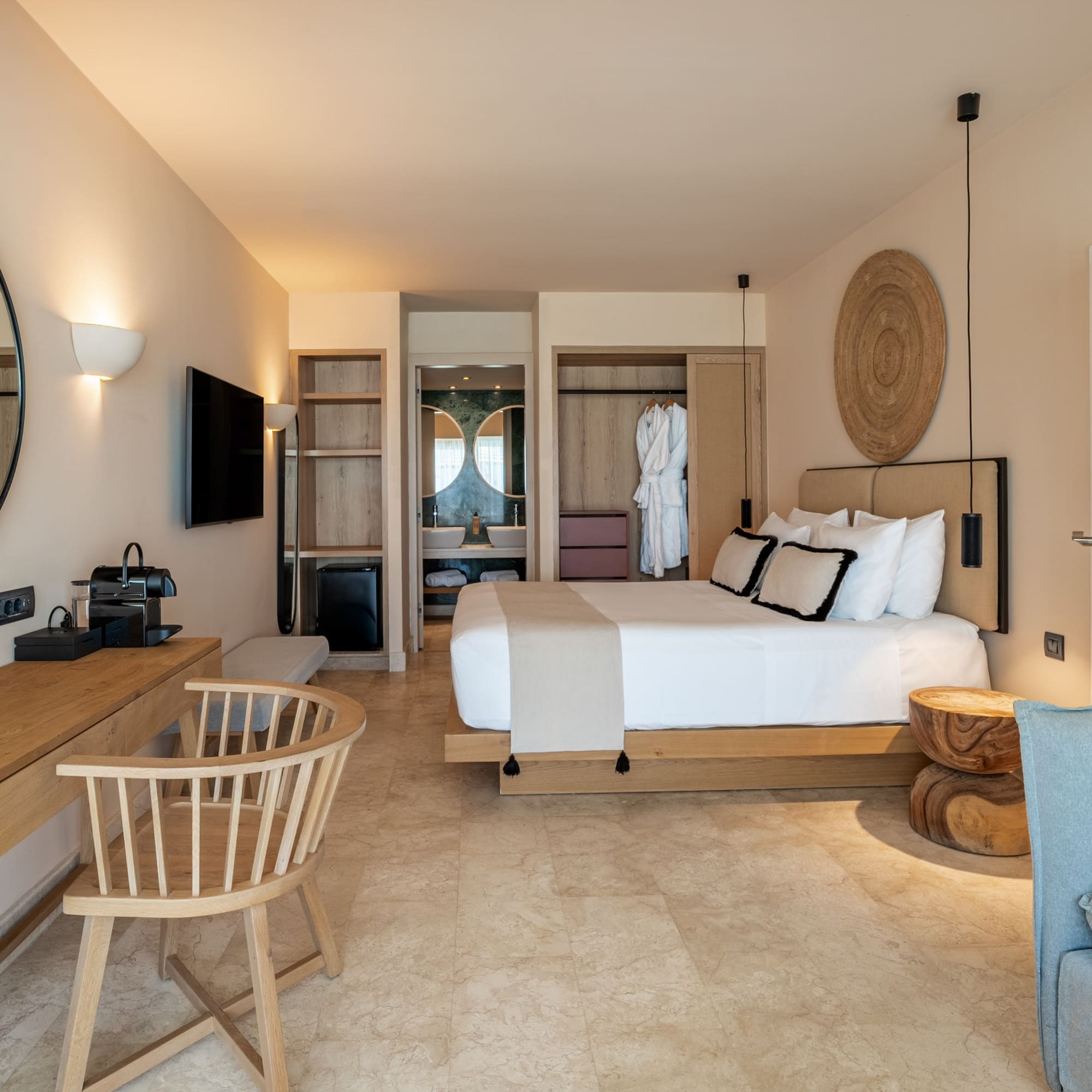 Modern hotel bedroom with white bed, wood furniture, and beige tiled floor.