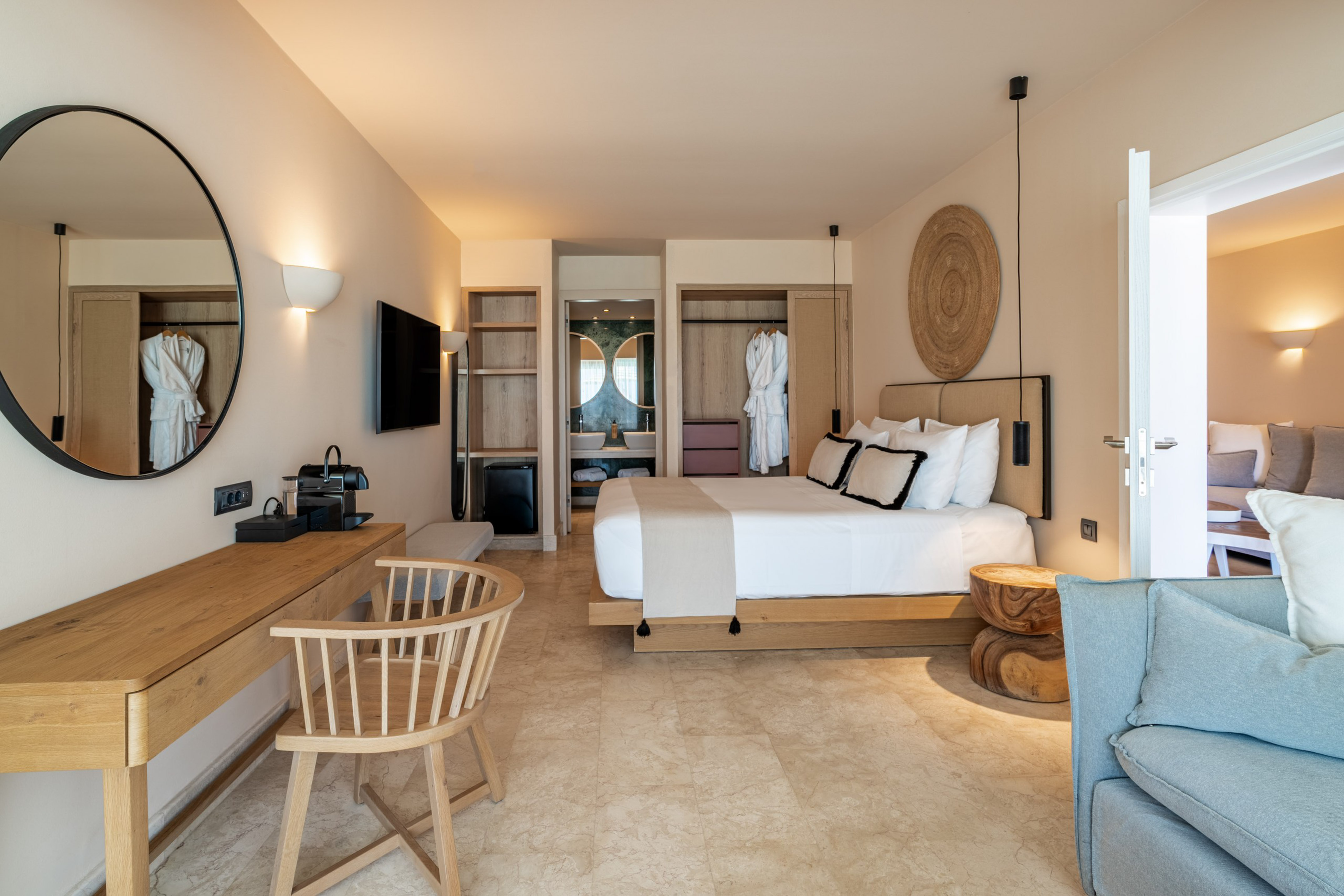 Modern hotel bedroom with white bed, wood furniture, and beige tiled floor.