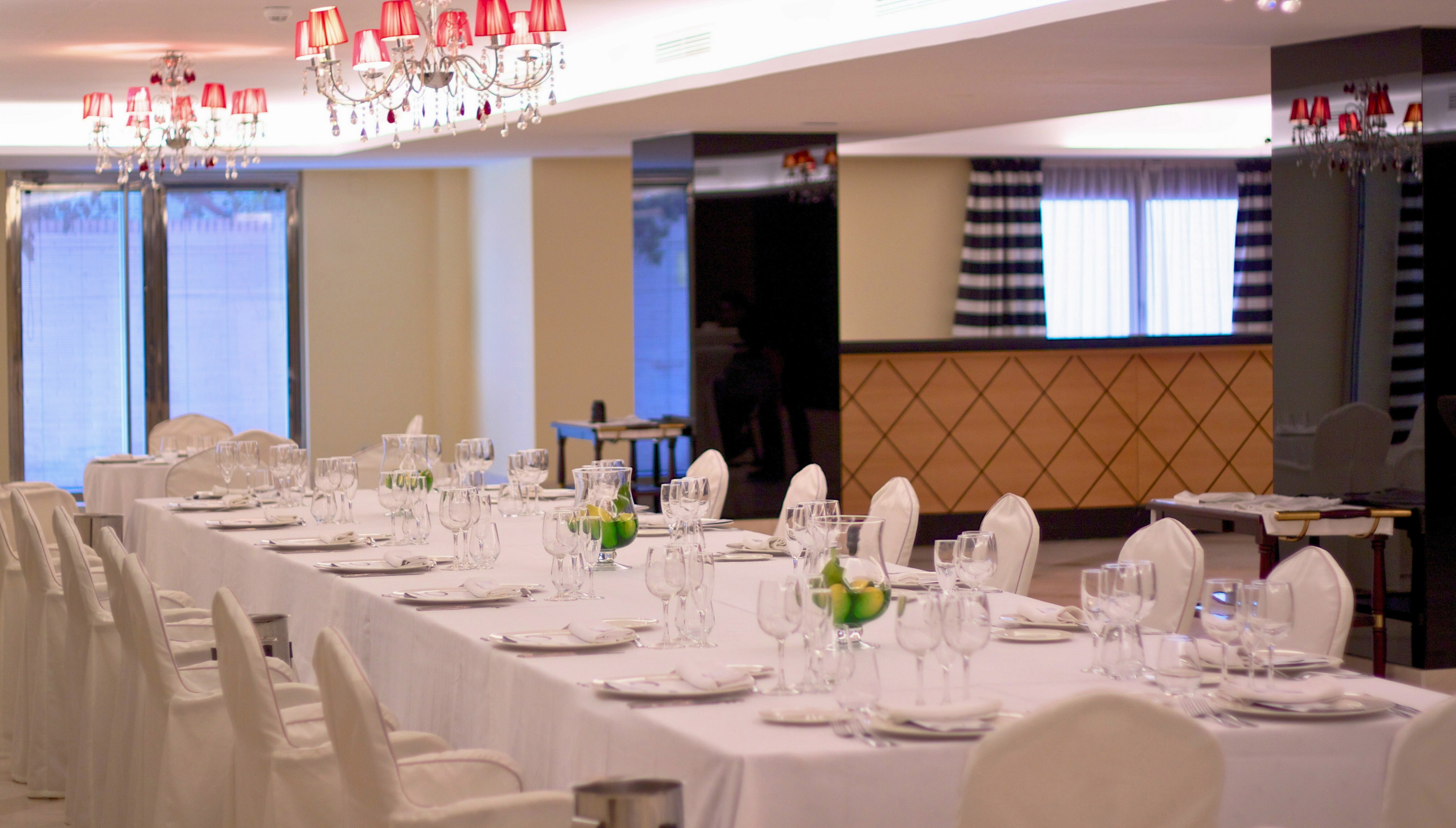 Formal dining table with white linens, place settings, and crystal chandeliers.