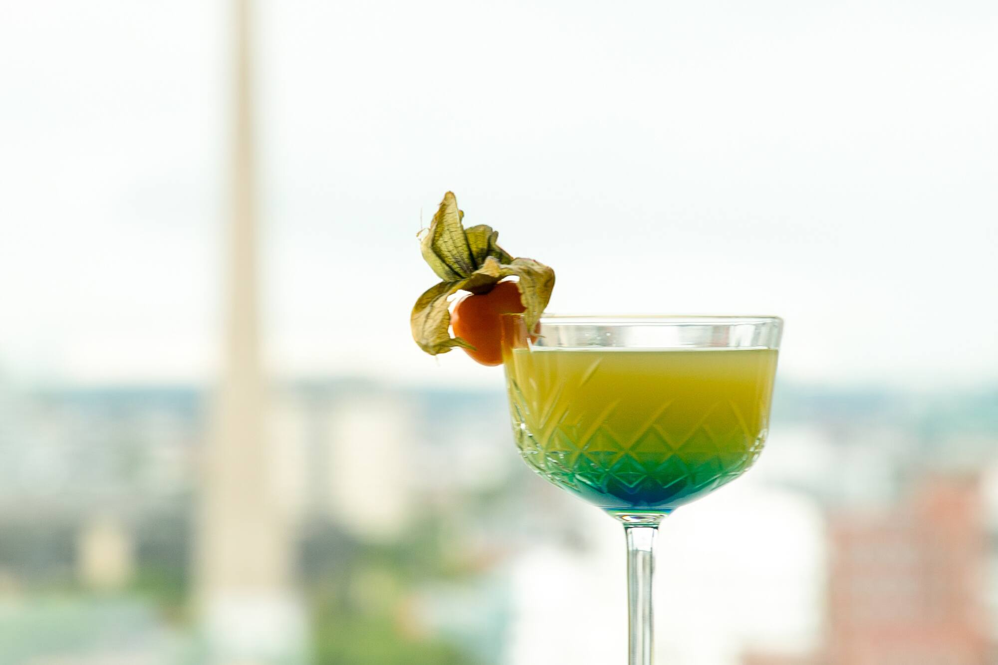 Gradient cocktail with physalis, Düsseldorf Rheinturm cityscape view.