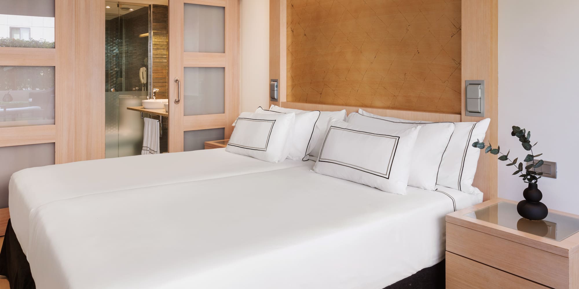a bed with white sheets and a wood headboard
