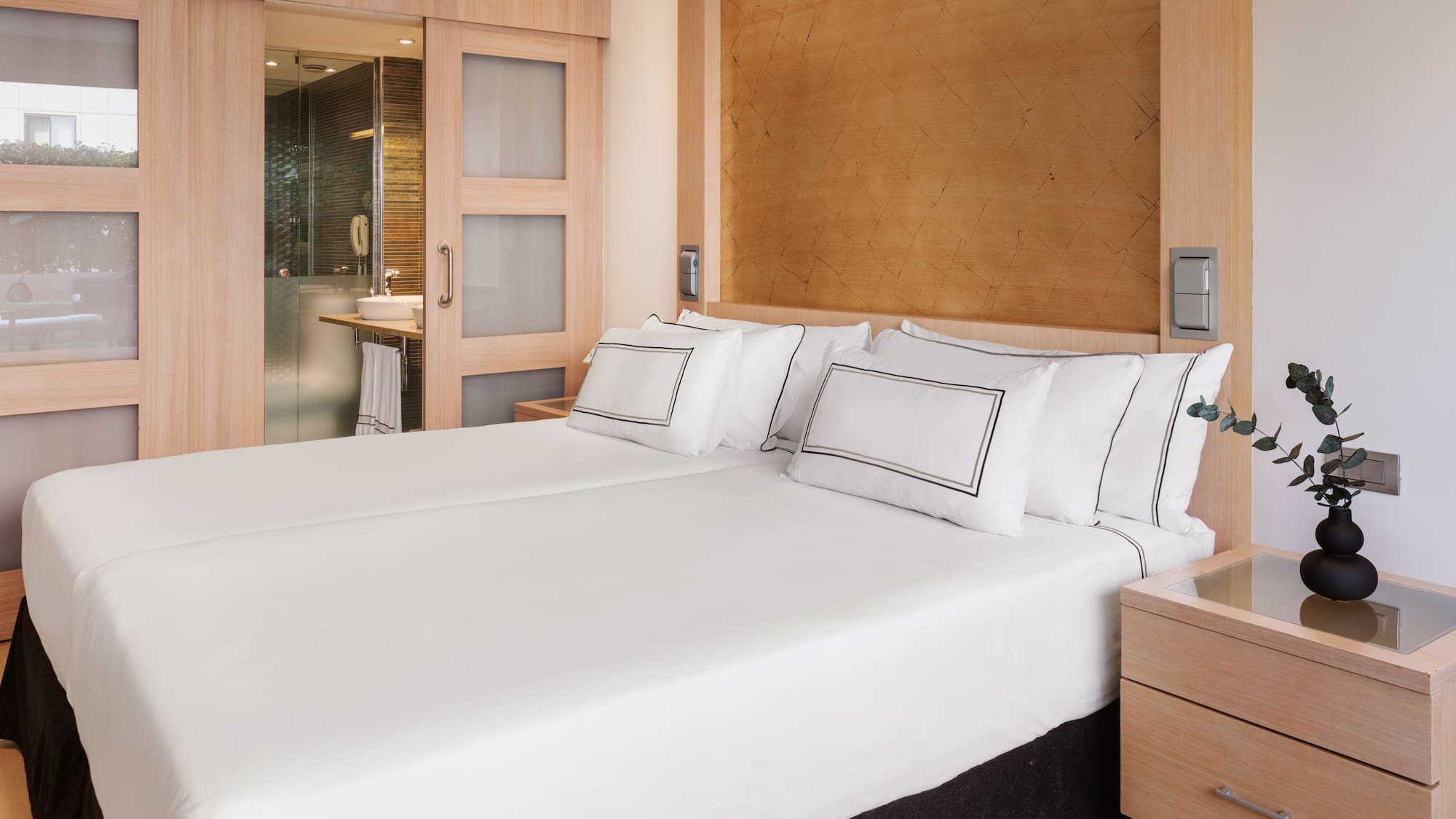 a bed with white sheets and a wood headboard