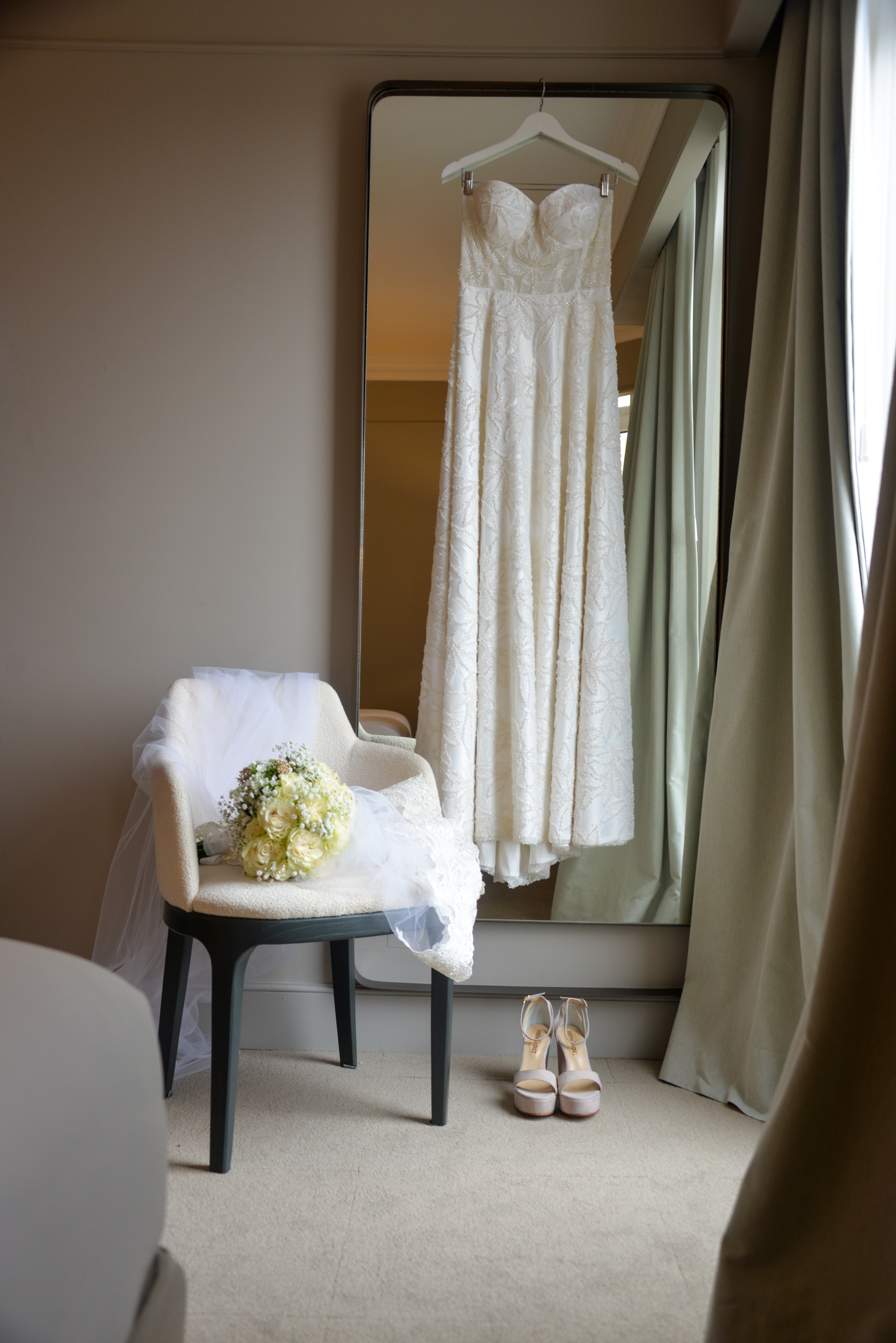 Bridal wedding dress, fresh bouquet, veil, and high heels ready for ceremony.