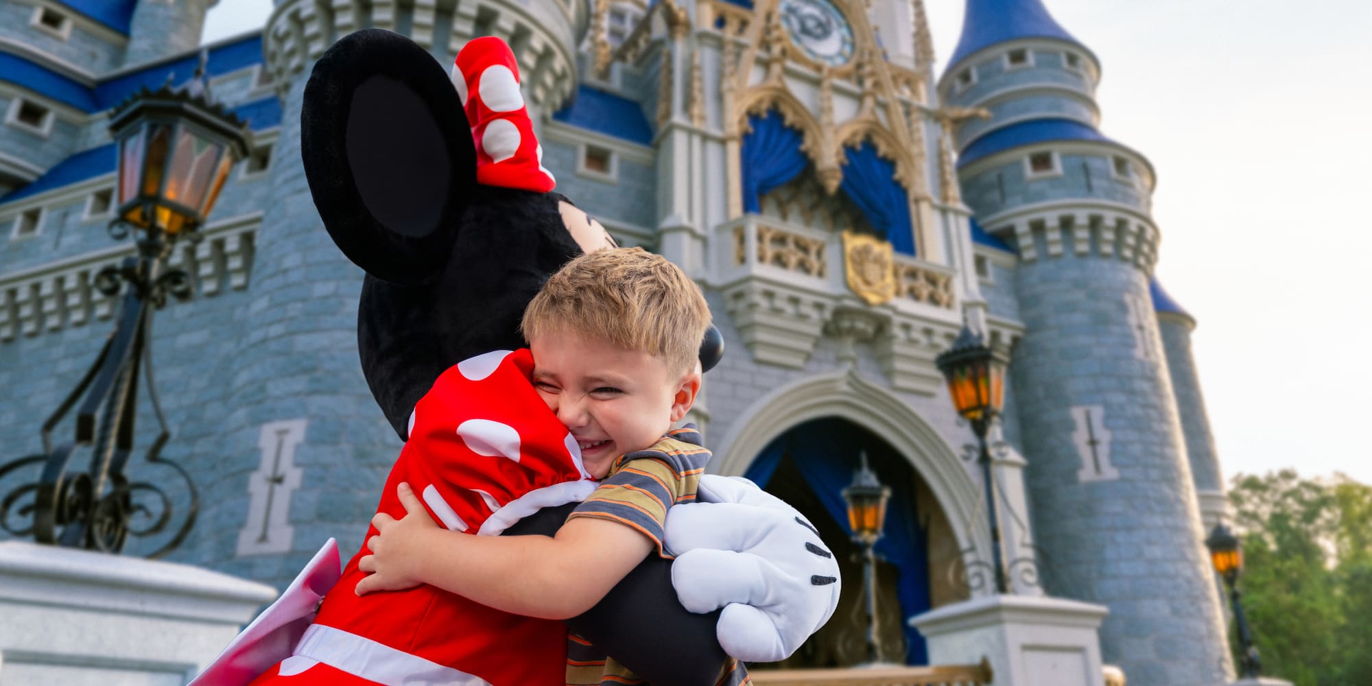 Happy boy hugs Minnie Mouse at Magic Kingdom's Cinderella Castle.