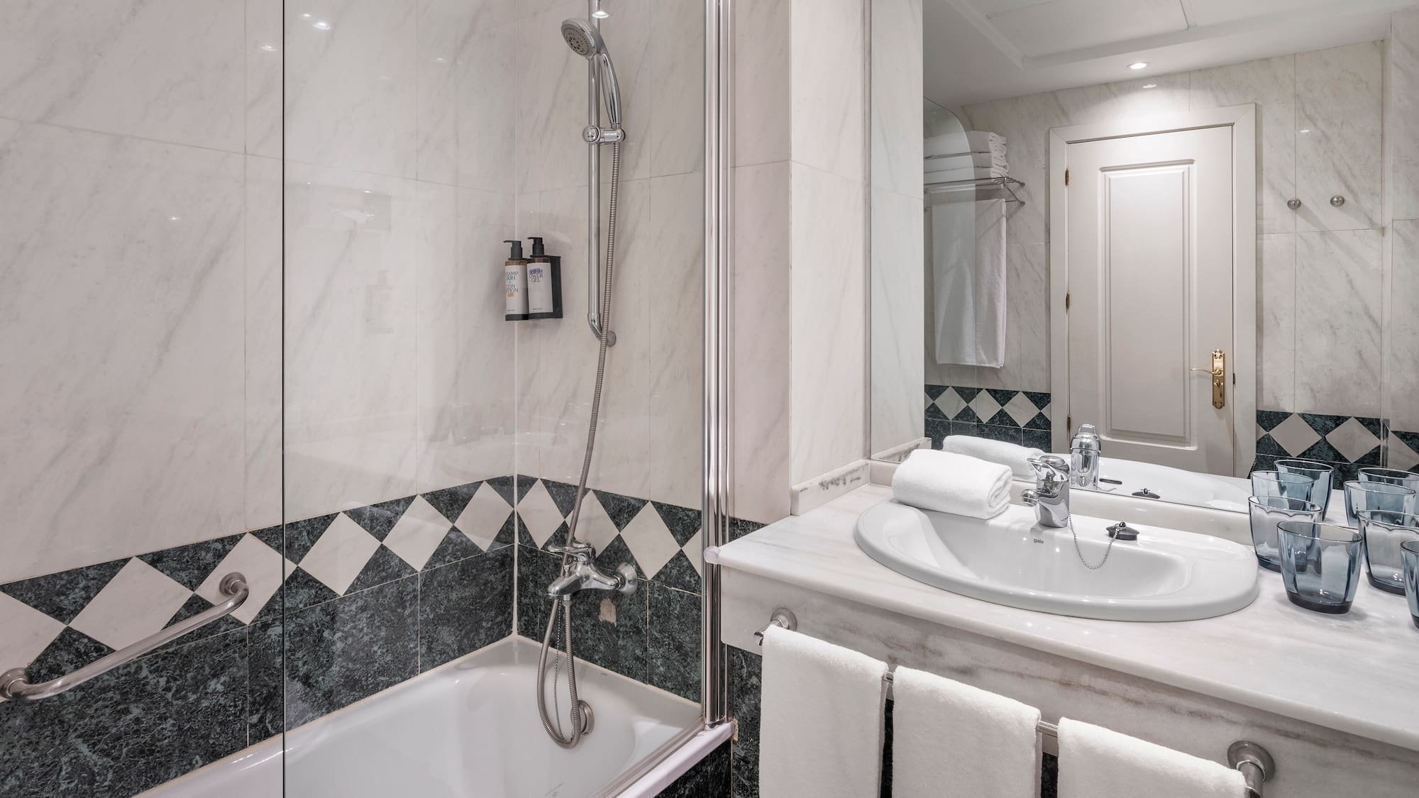 Modern bathroom with marble shower, bathtub, sink, and vanity.