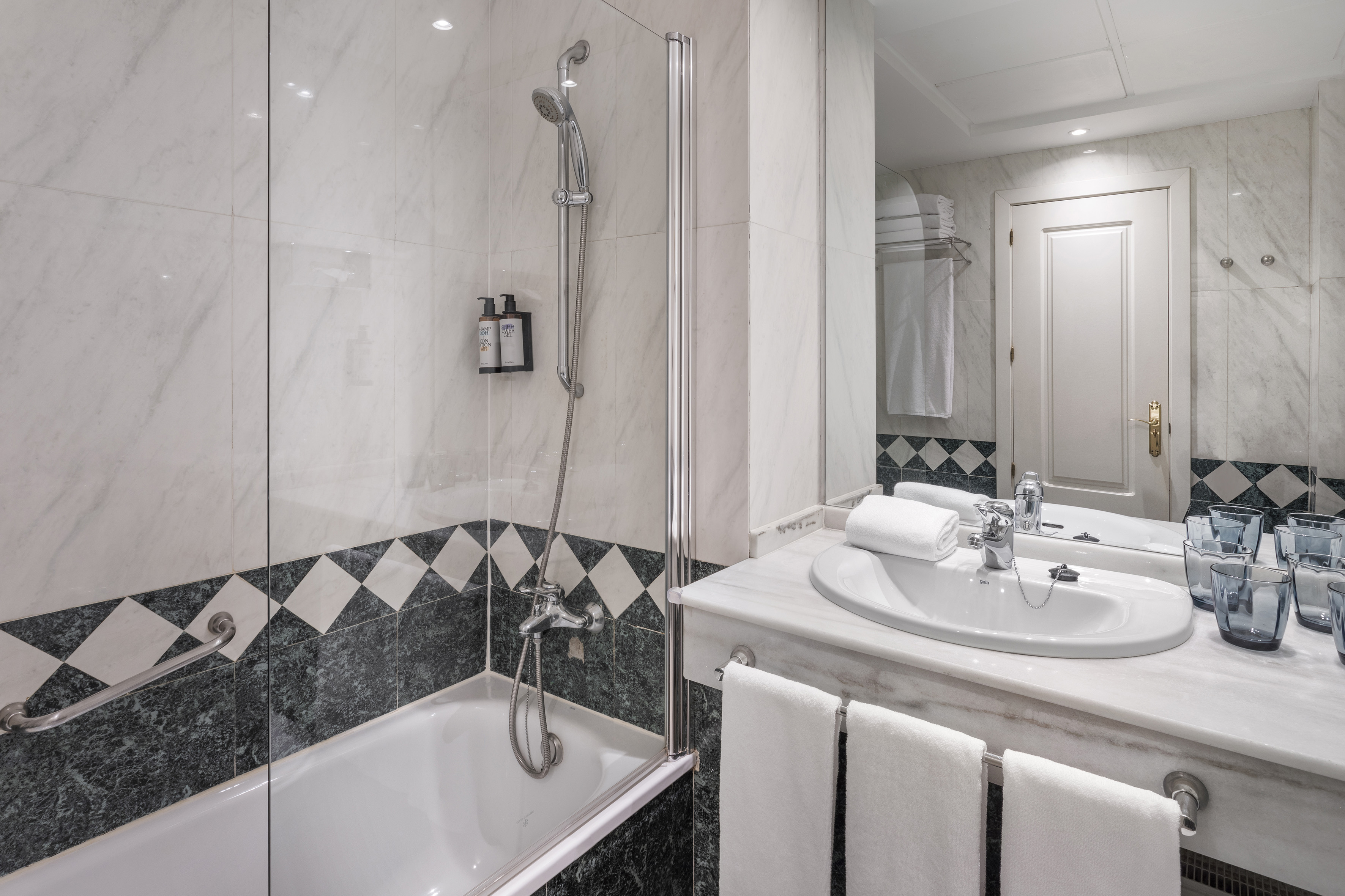 Modern bathroom with marble shower, bathtub, sink, and vanity.