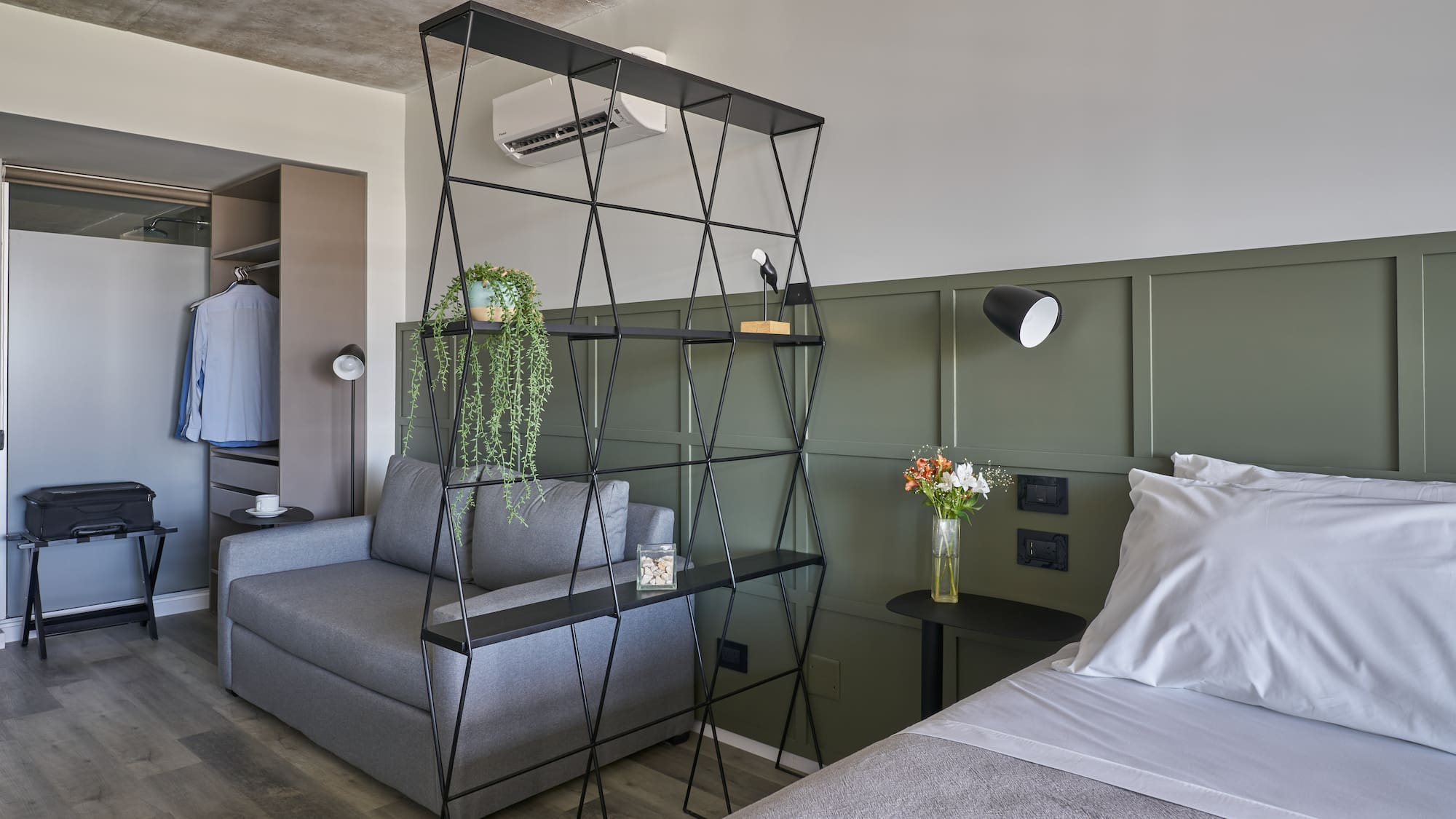 Modern studio: bed, sofa, black geometric divider, green panel wall.