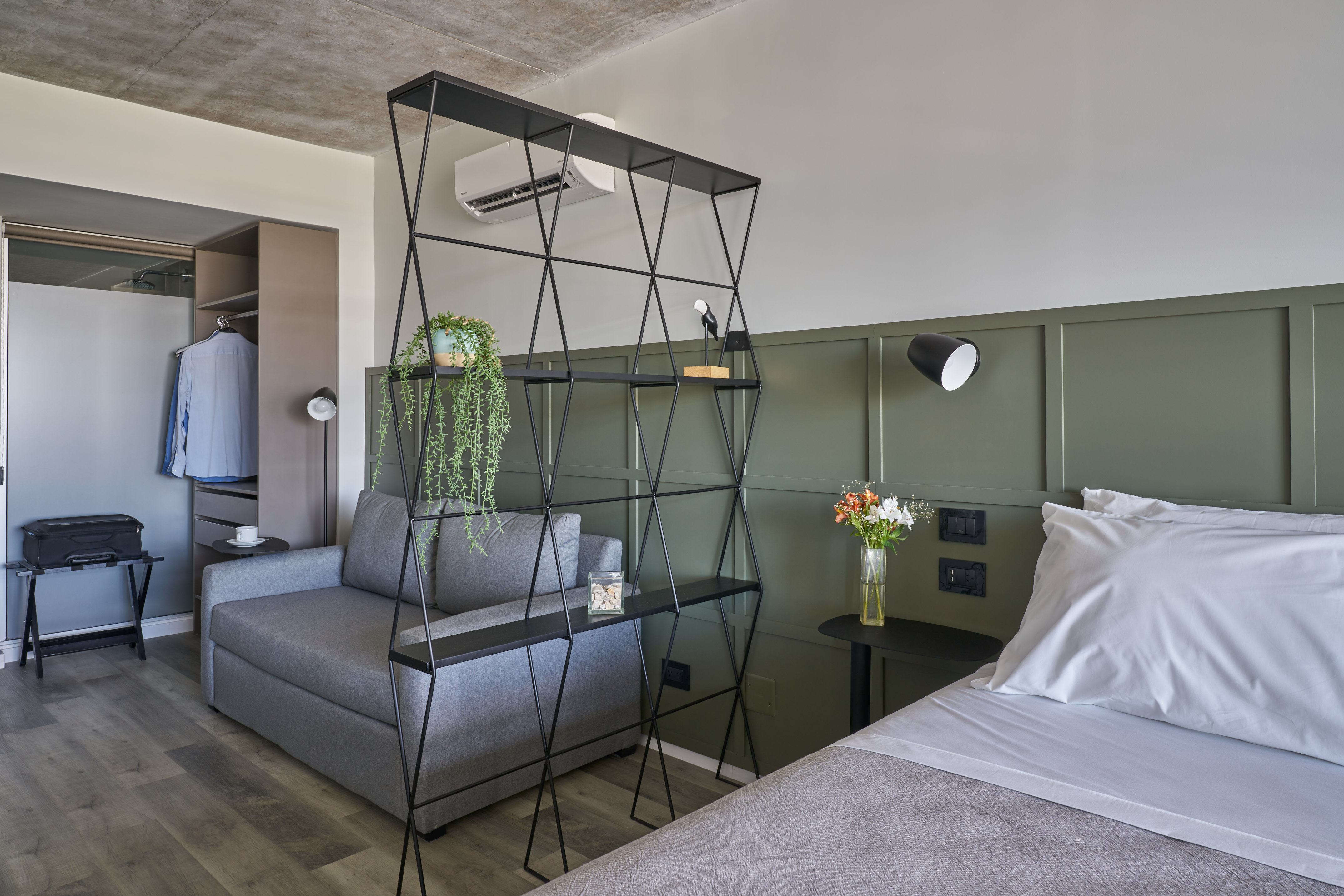 Modern studio: bed, sofa, black geometric divider, green panel wall.