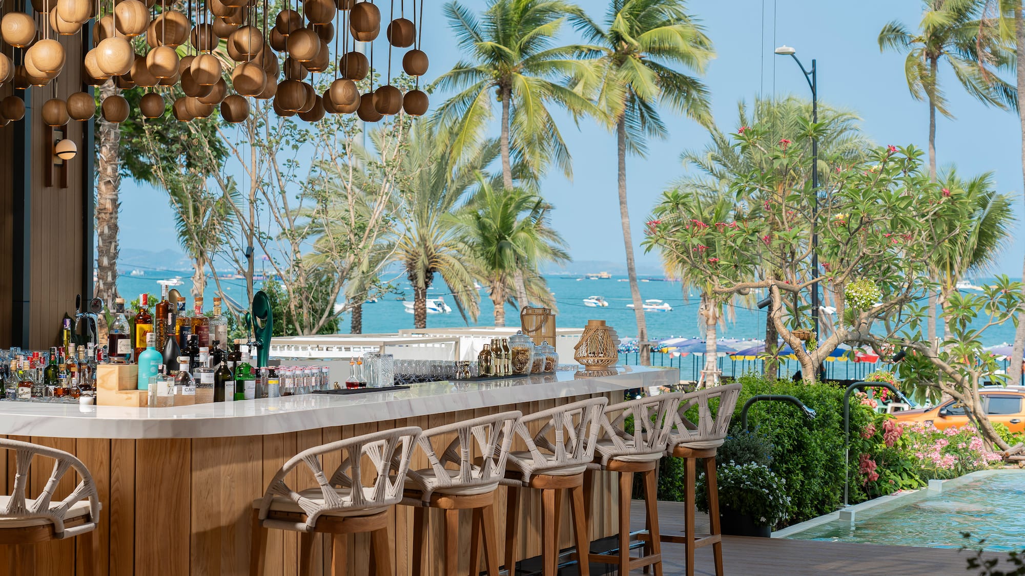 Tropical bar with ocean view, palm trees, and stylish modern decor.