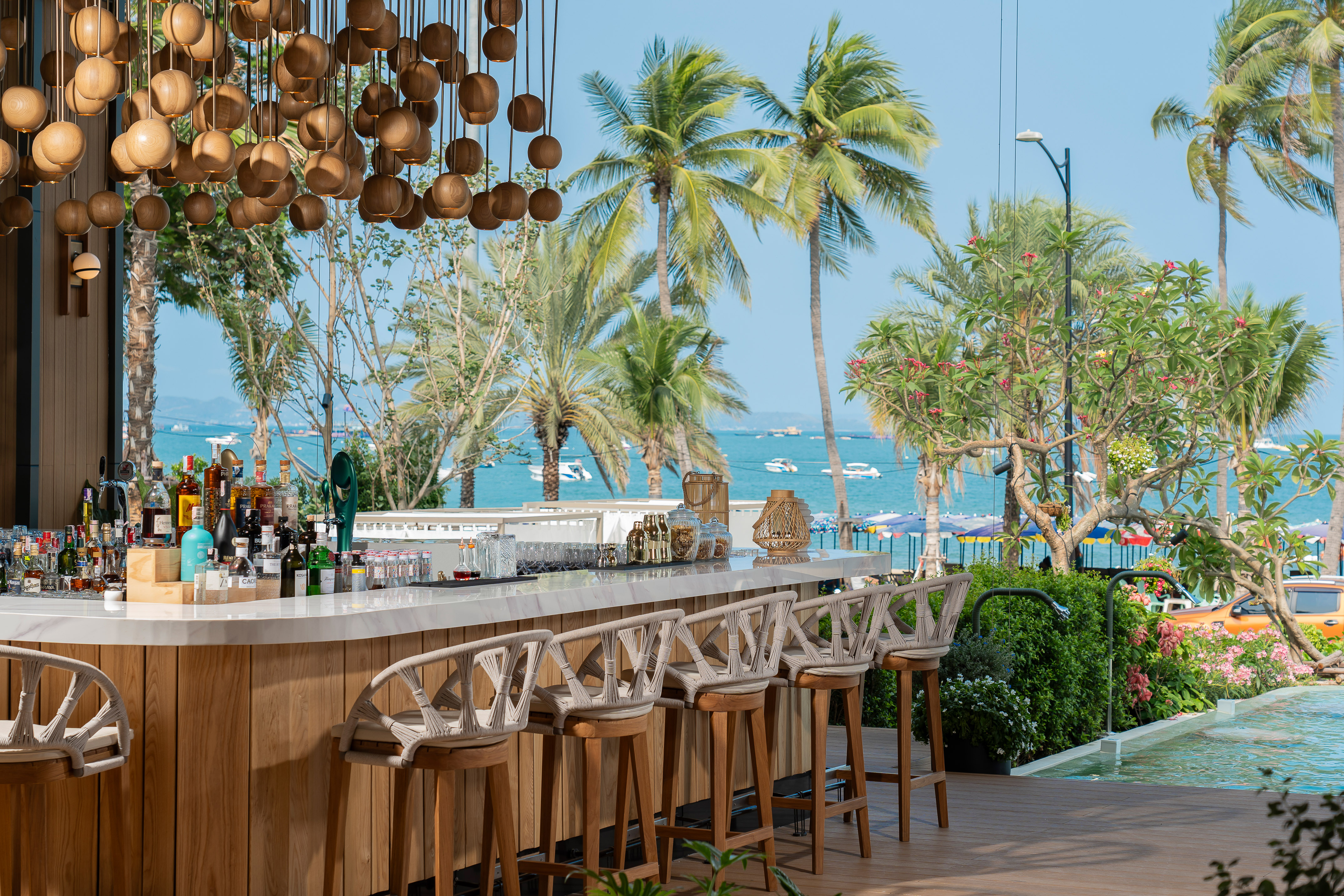 a bar with chairs and a pool in the background