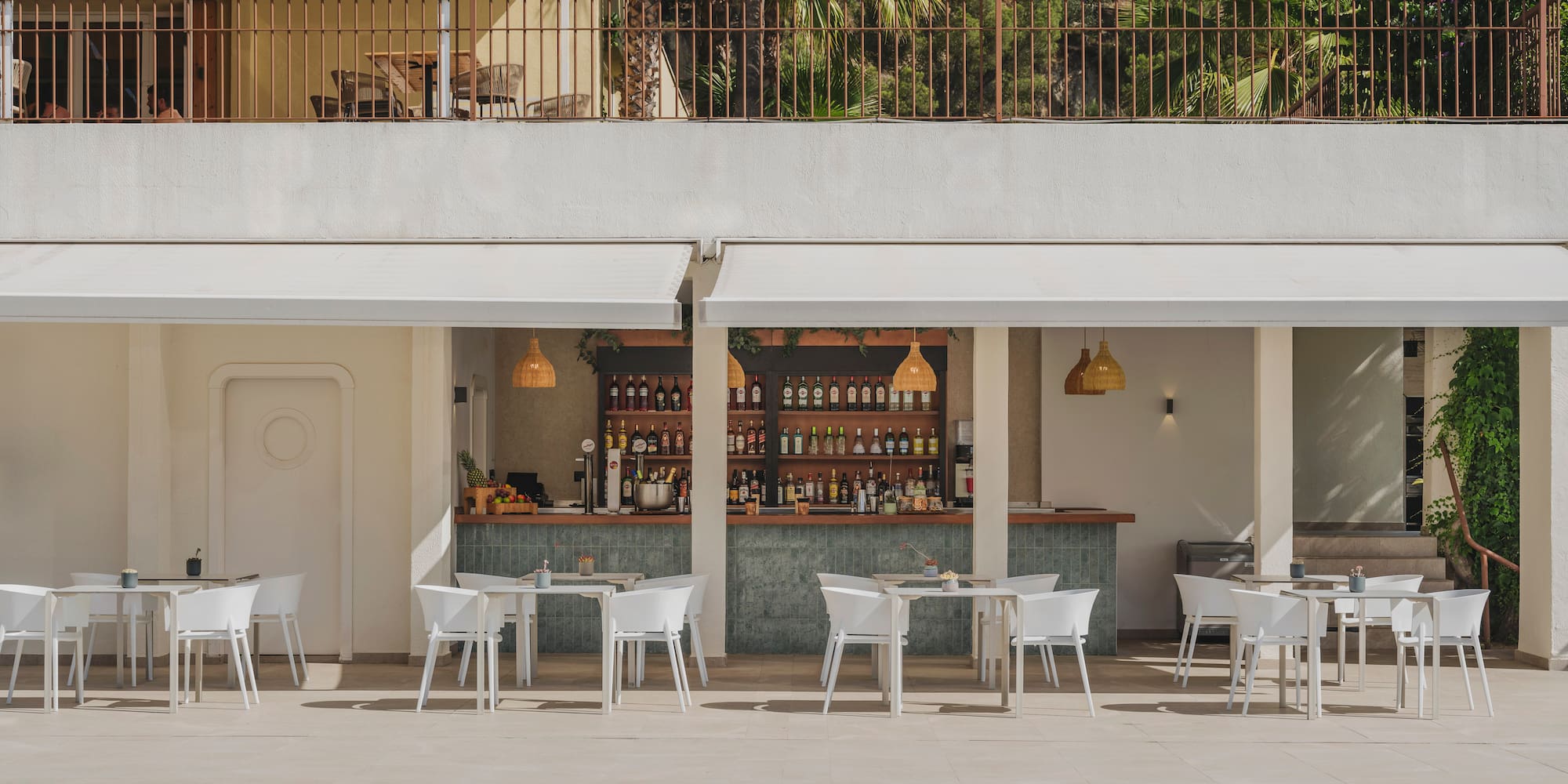 Outdoor resort bar with poolside tables, chairs, and palm trees.