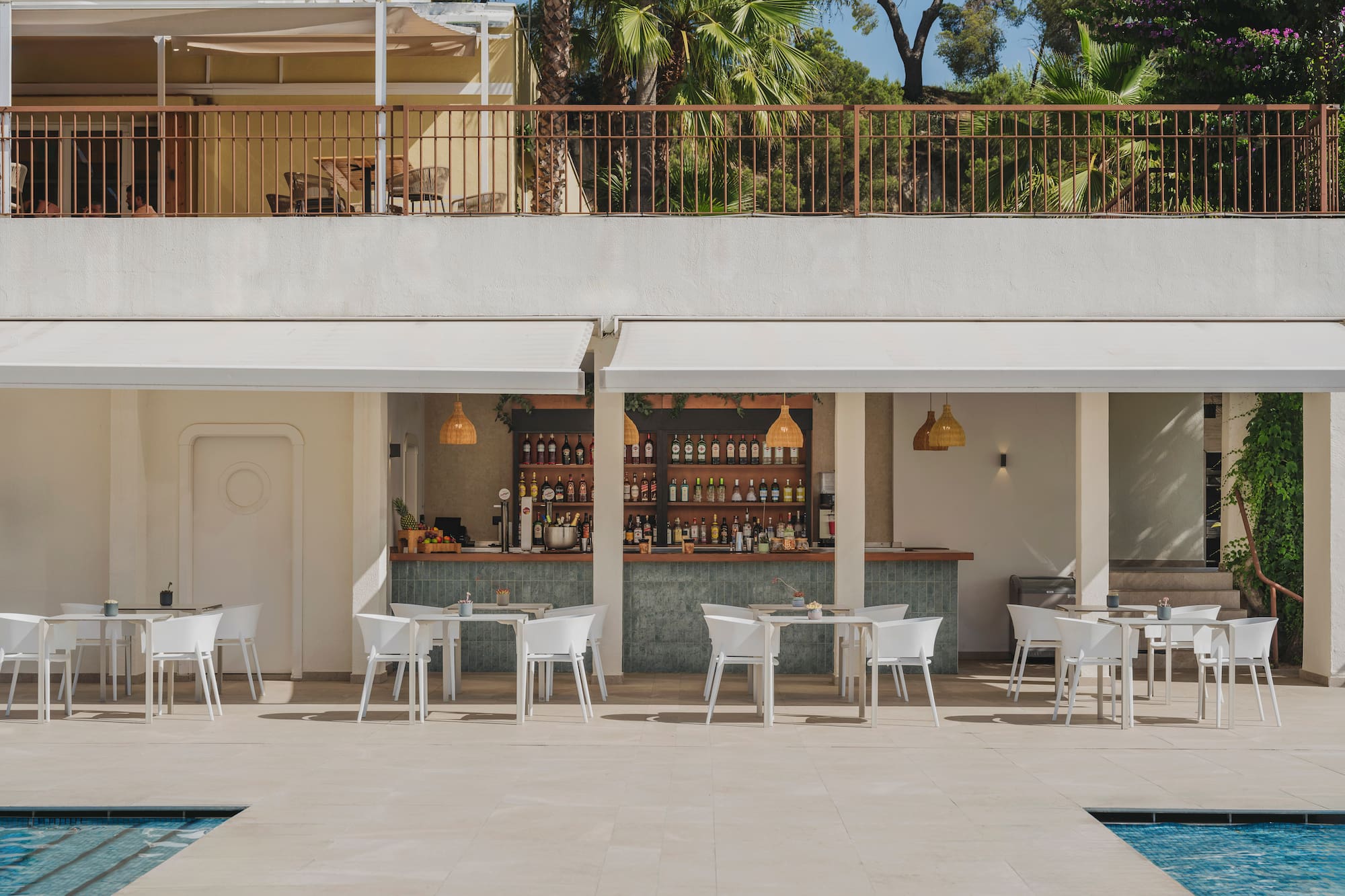 Outdoor resort bar with poolside tables, chairs, and palm trees.