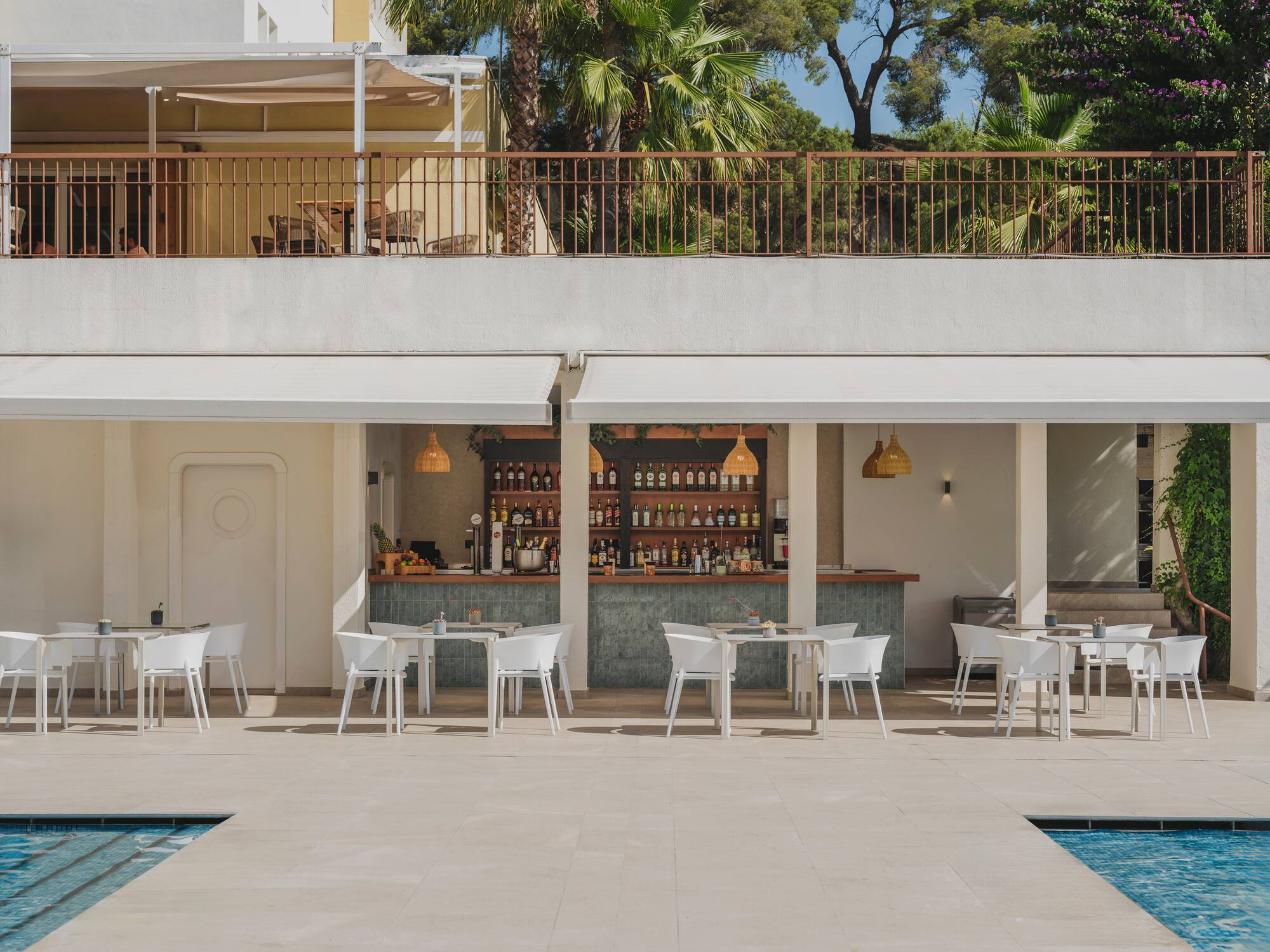 Poolside bar and outdoor dining patio with white furniture at a sunny resort.
