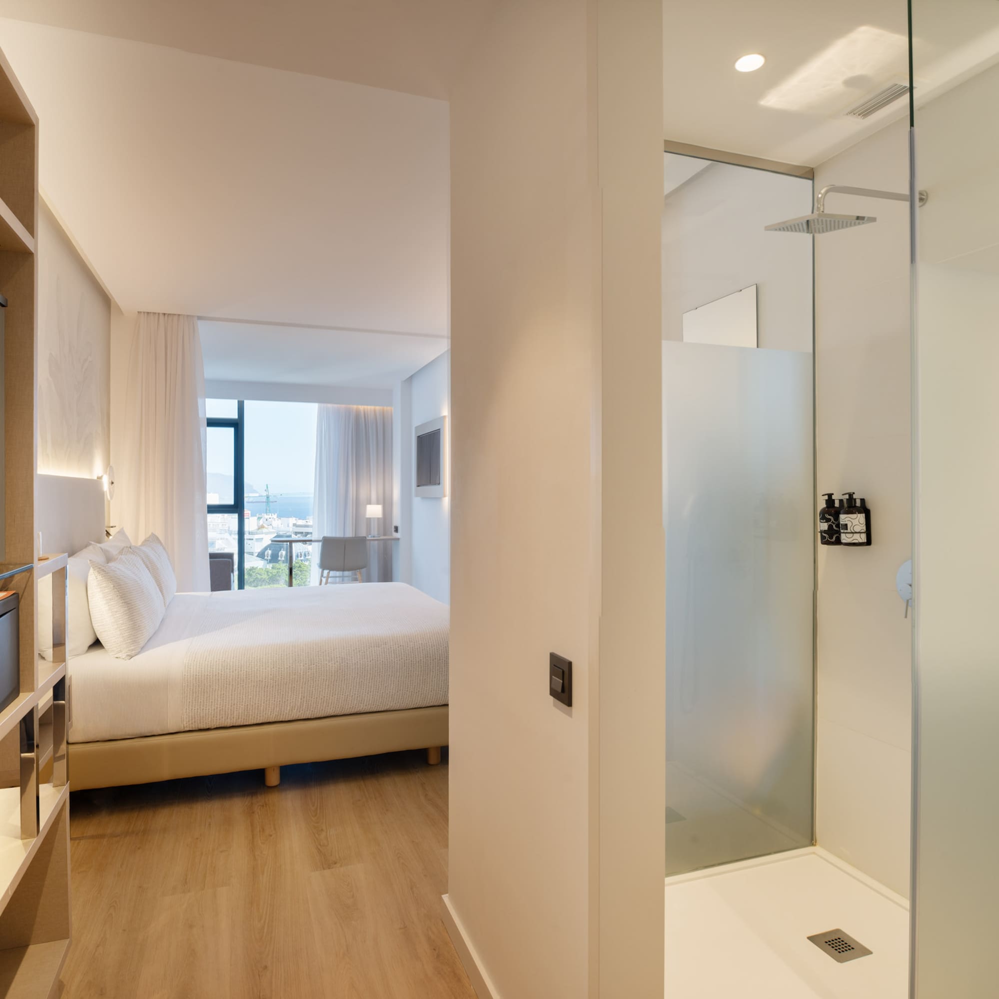 a bedroom with a glass shower and a bed