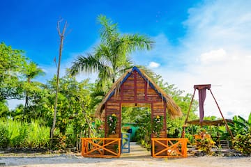 a wooden structure with a thatched roof and a palm tree