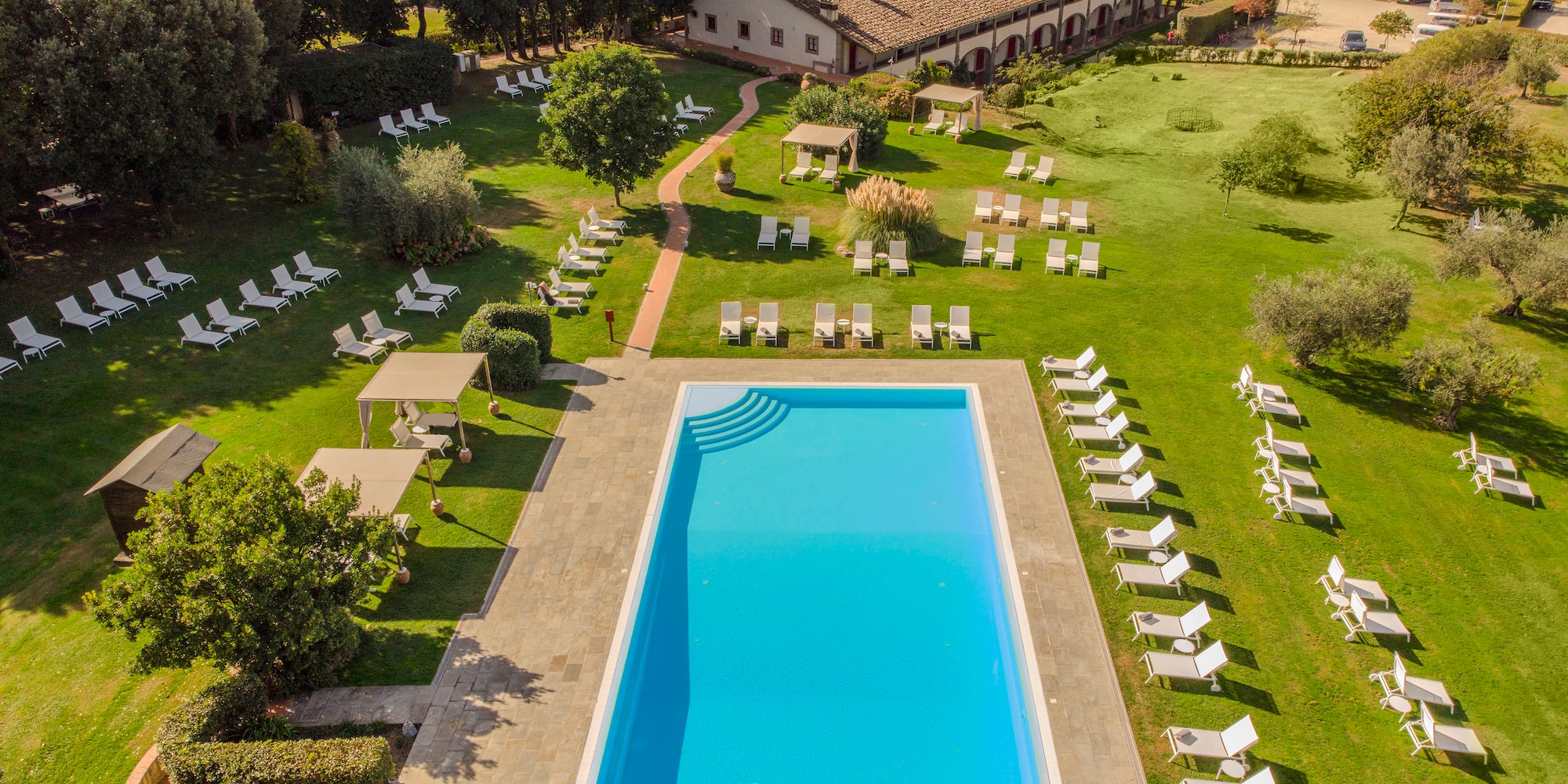 a pool and lawn with chairs and trees