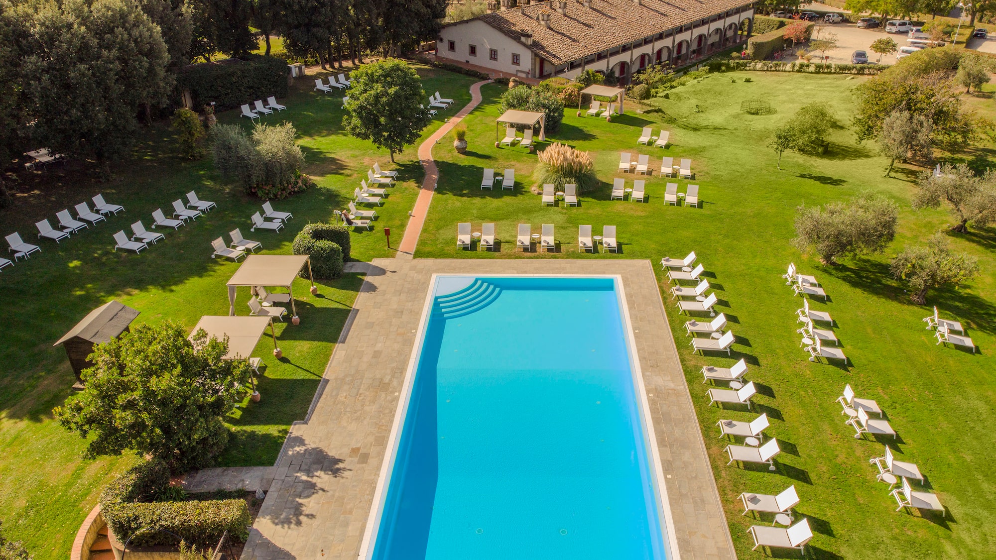 a pool and lawn with chairs and trees
