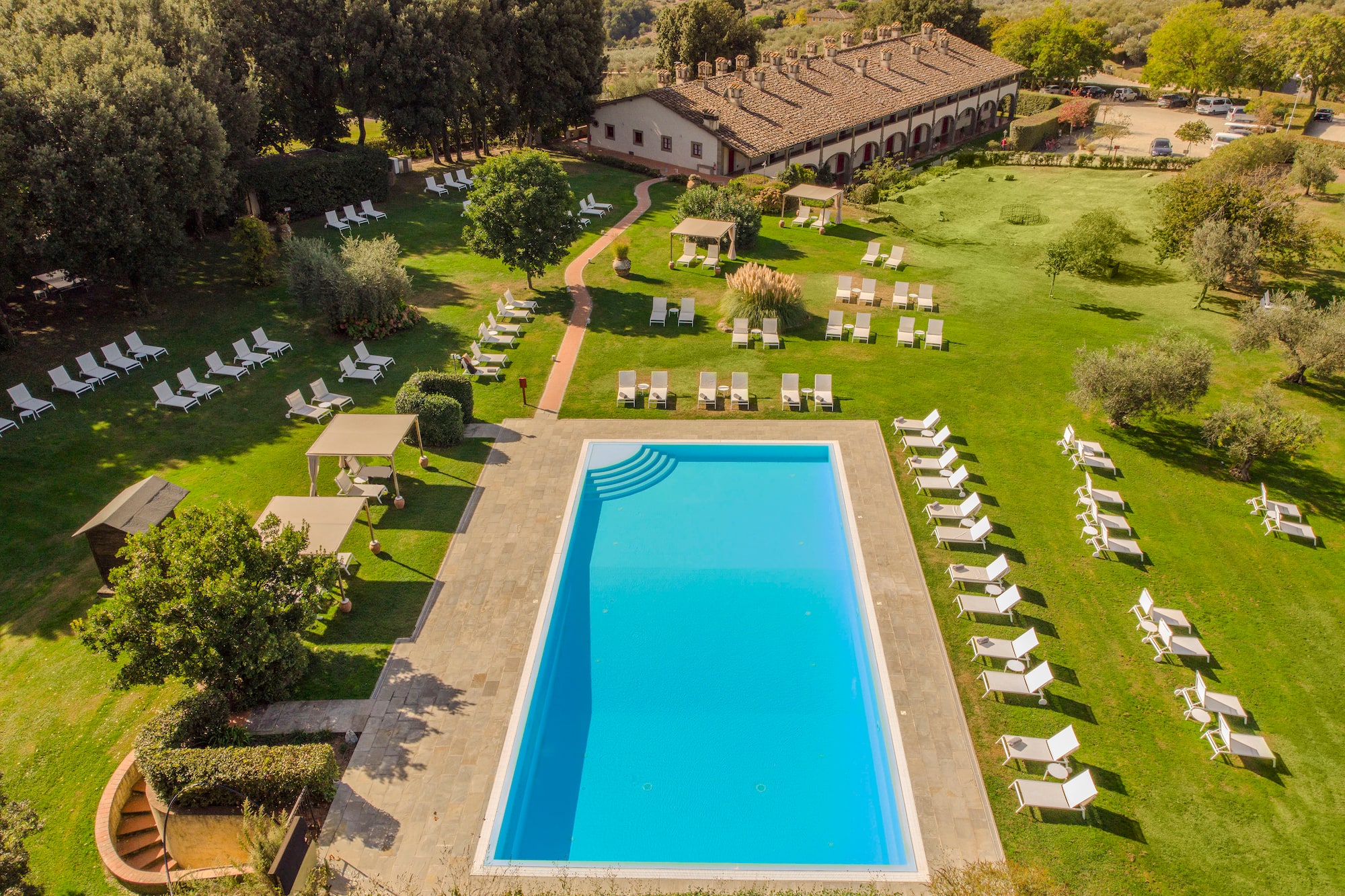 a pool and lawn with chairs and trees