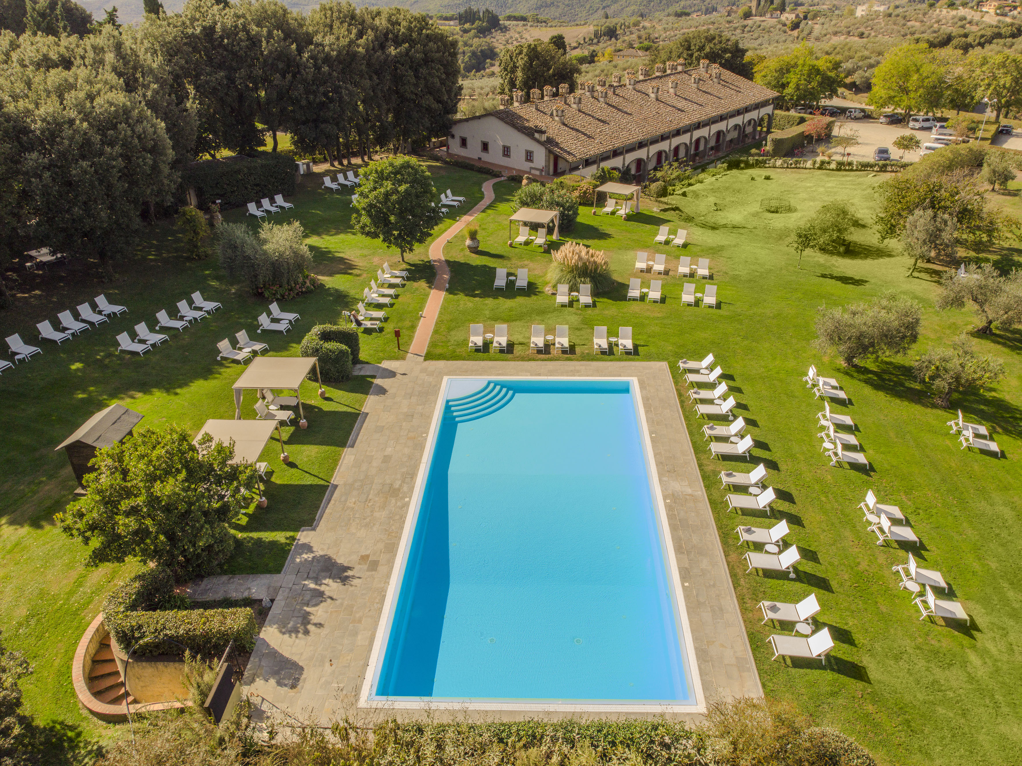 a pool and lawn with chairs and trees