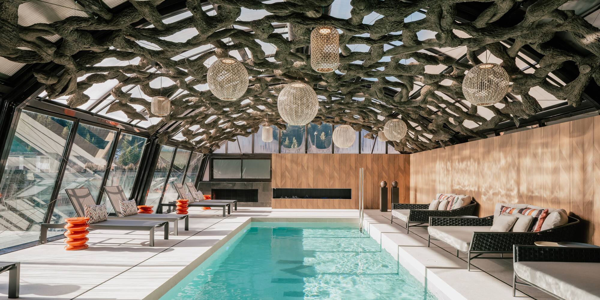 Luxurious indoor pool with organic root ceiling and modern spa loungers.