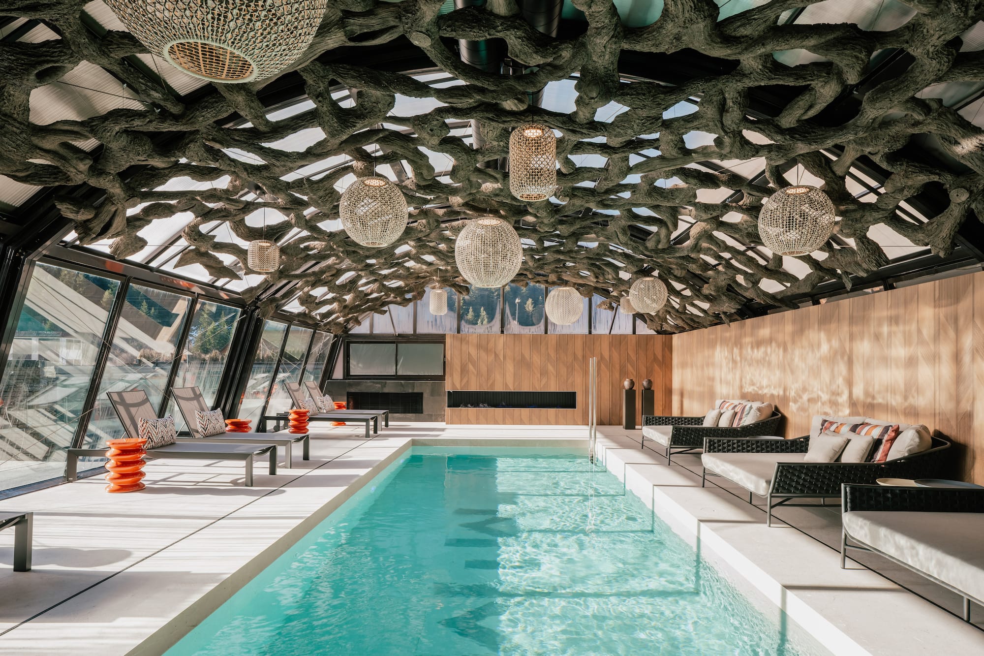 Luxury indoor pool with organic tree root ceiling and modern lounge seating.