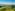 Helicopter over rolling green vineyards and hilltop village in a sunny wine region.