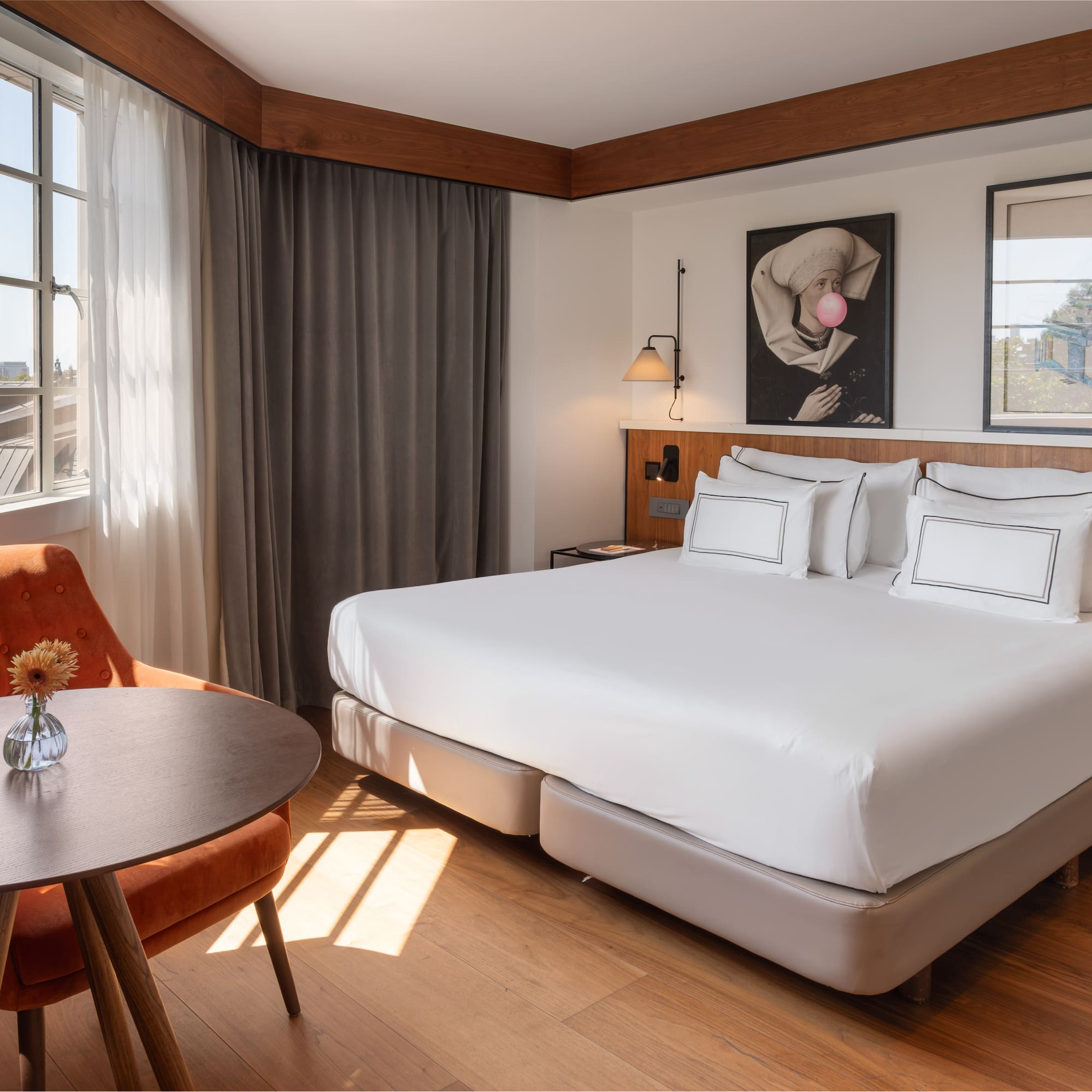 Modern hotel room with large bed, cozy seating area, and sunlit window.