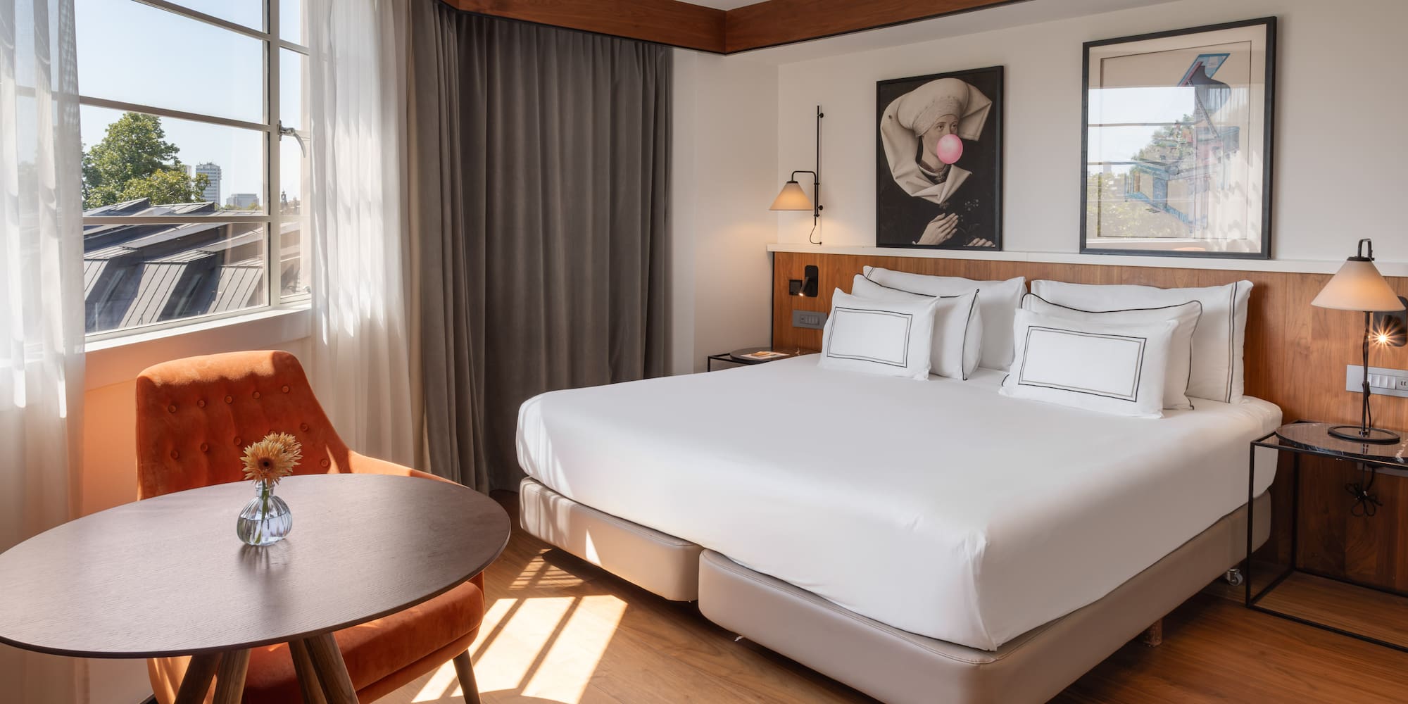 Modern hotel room with large bed, cozy seating area, and sunlit window.