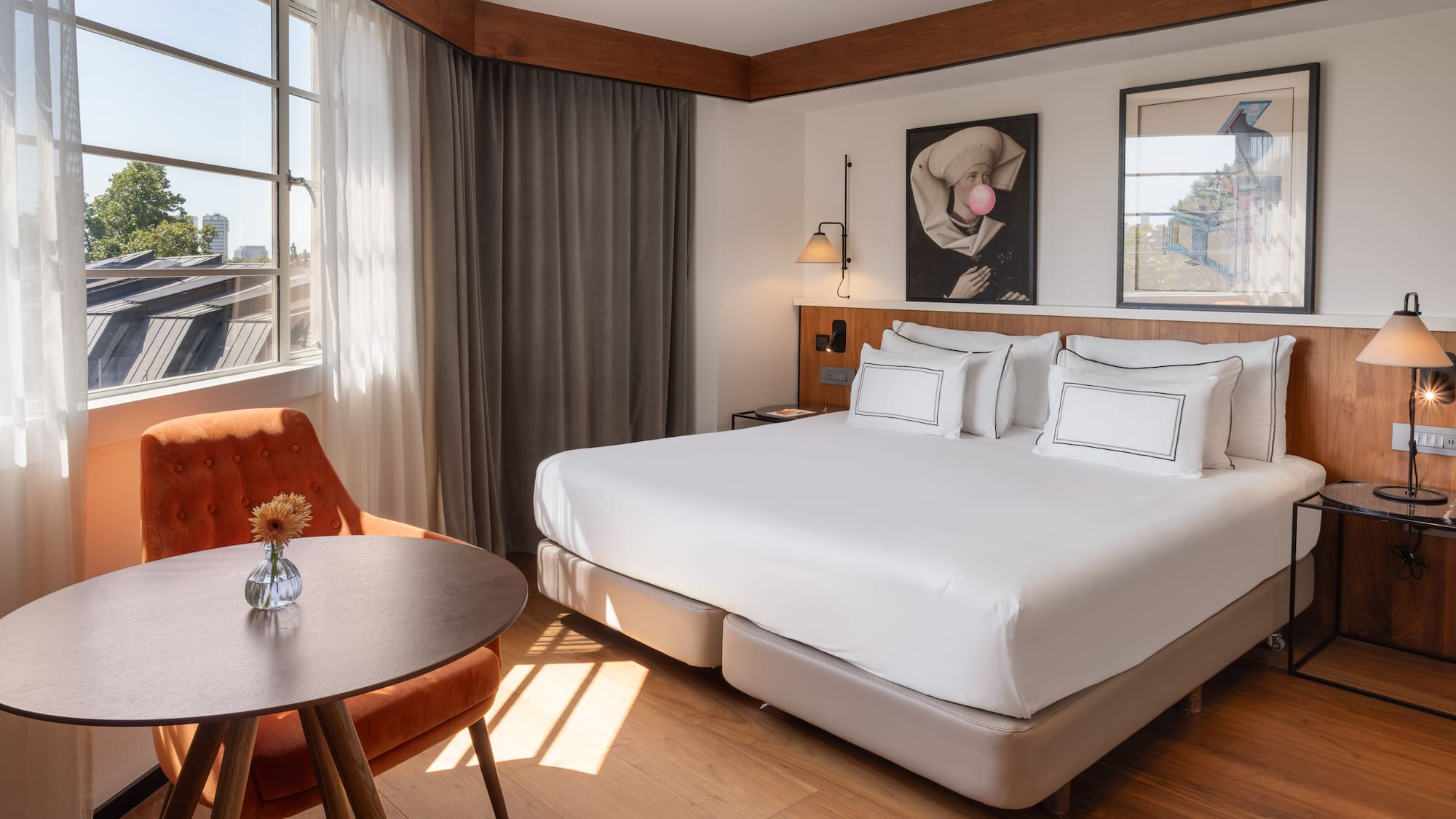 Modern hotel room with large bed, cozy seating area, and sunlit window.