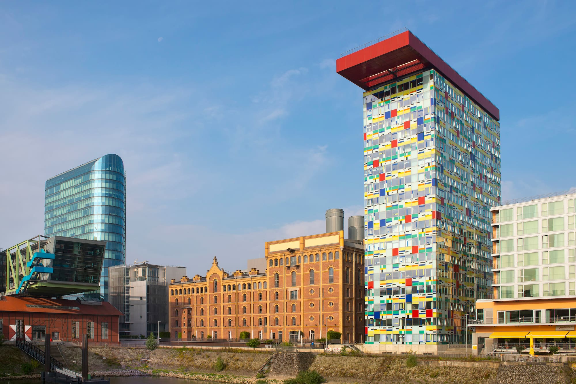 Modern skyscrapers, historic brick building, and canal in urban cityscape.