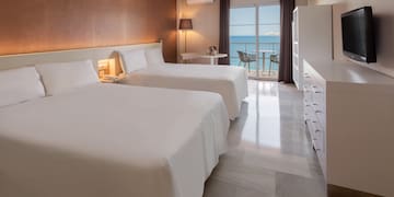 a room with two beds and a balcony overlooking the ocean