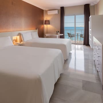 a room with two beds and a balcony overlooking the ocean