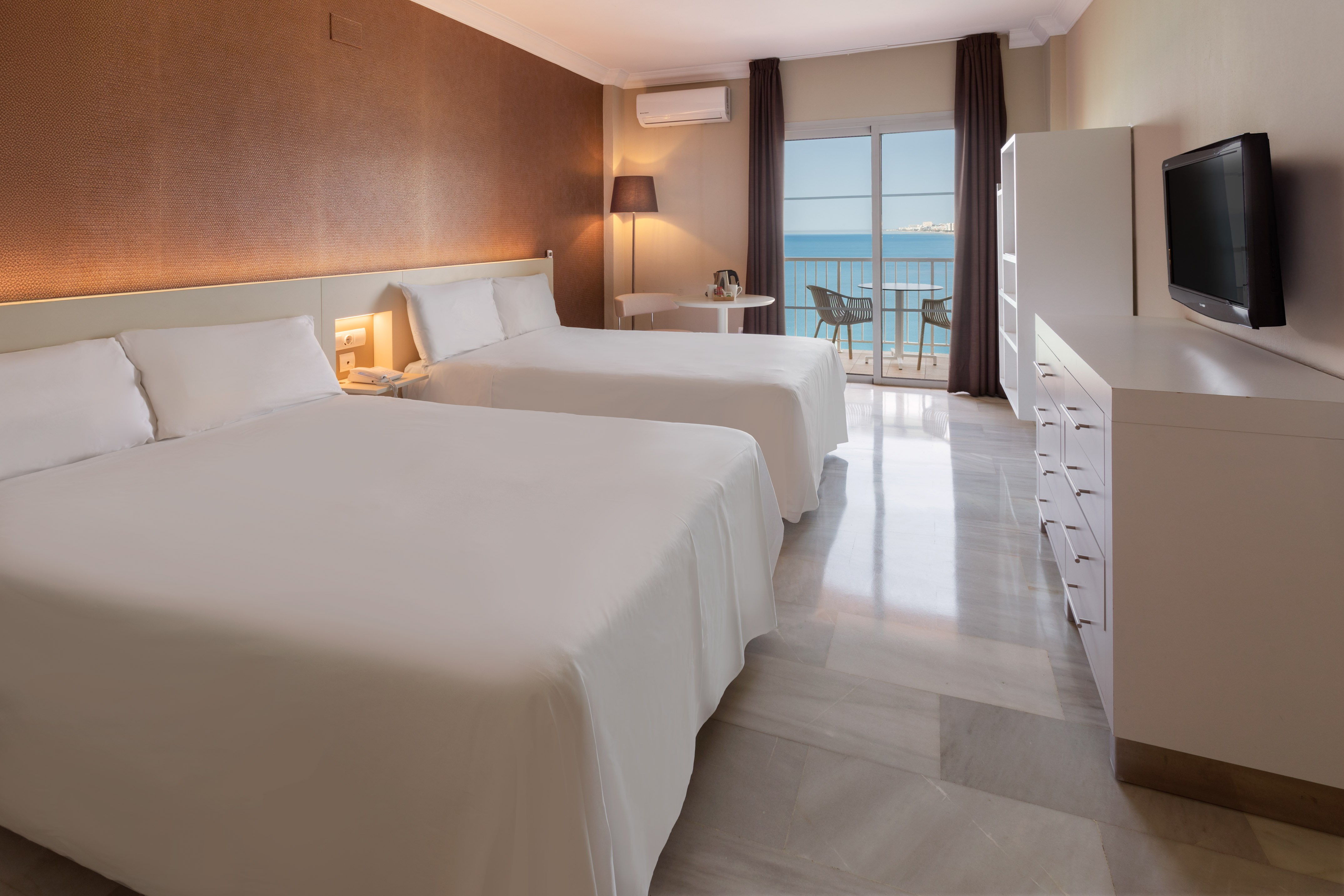 a room with two beds and a balcony overlooking the ocean