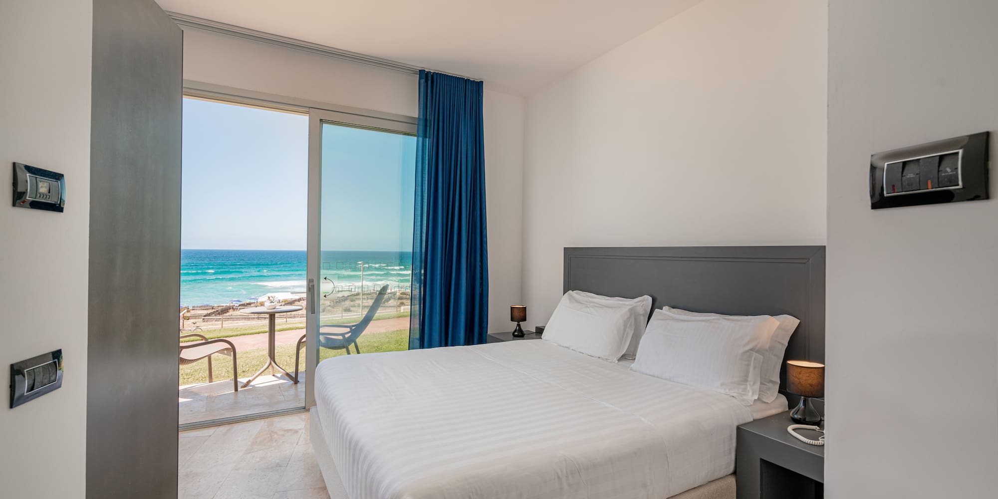 a bed with a glass door and a view of the ocean