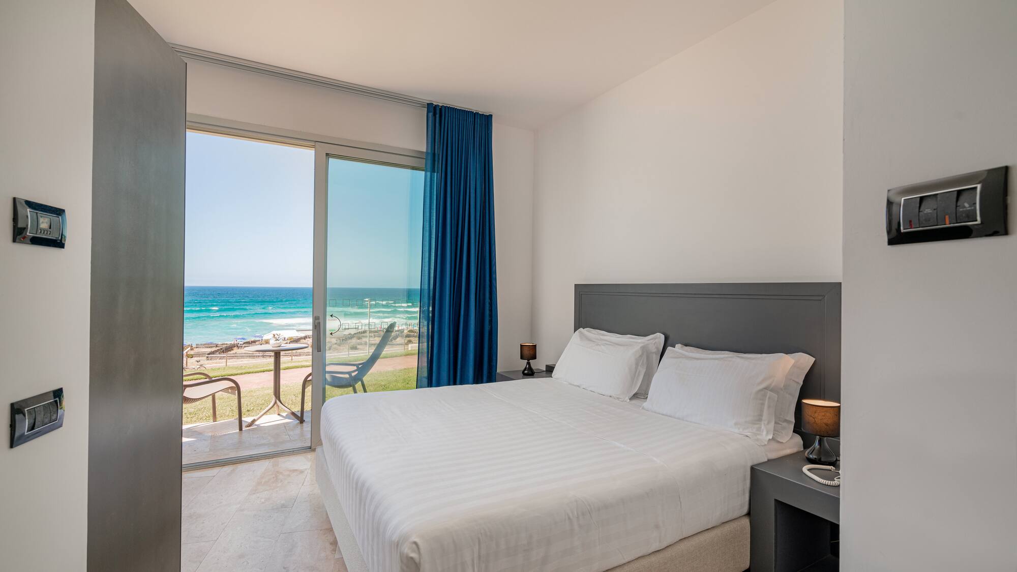a bed with a glass door and a view of the ocean