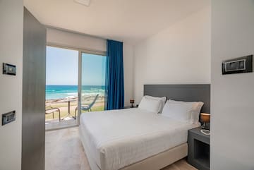 a bed with a glass door and a view of the ocean
