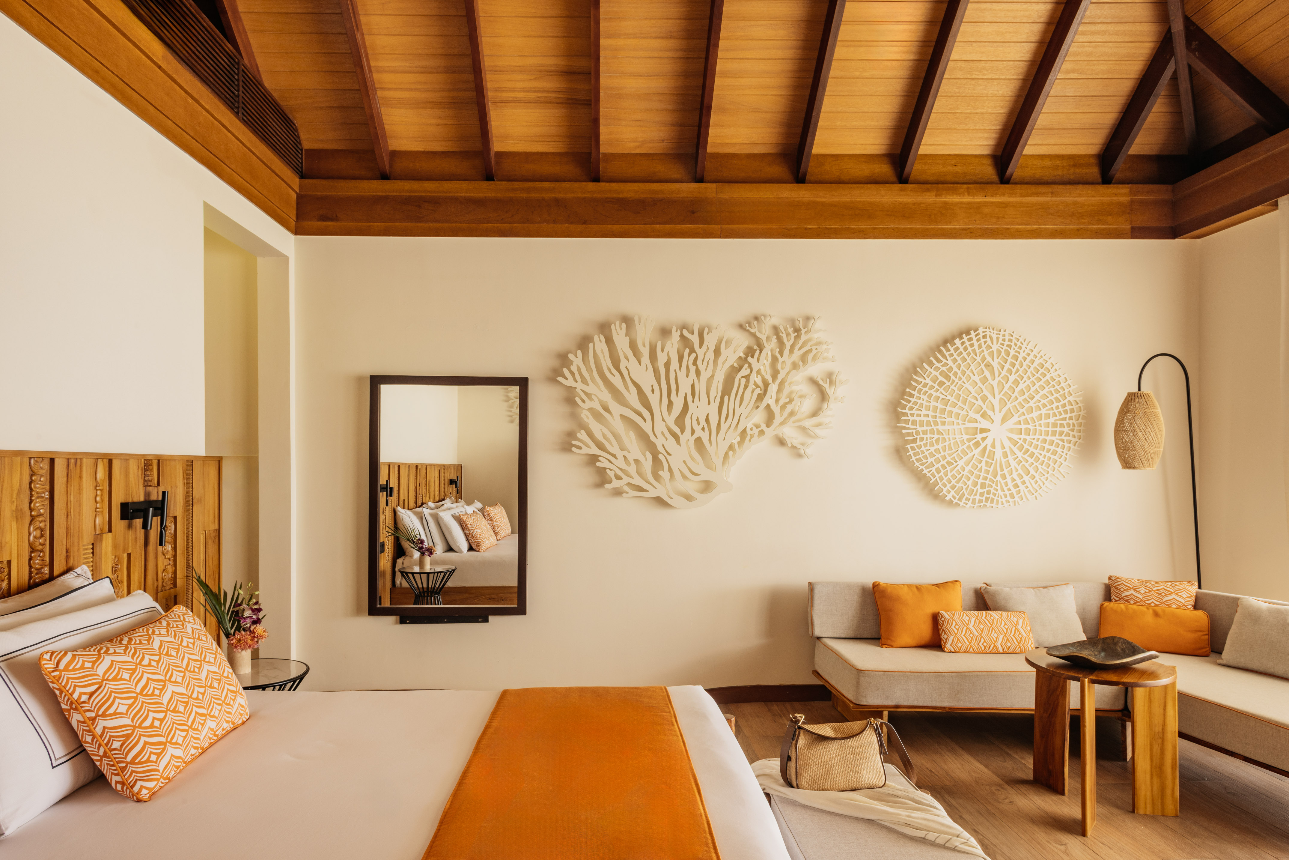 Luxury resort bedroom with wood ceiling, coral decor, and orange soft furnishings.