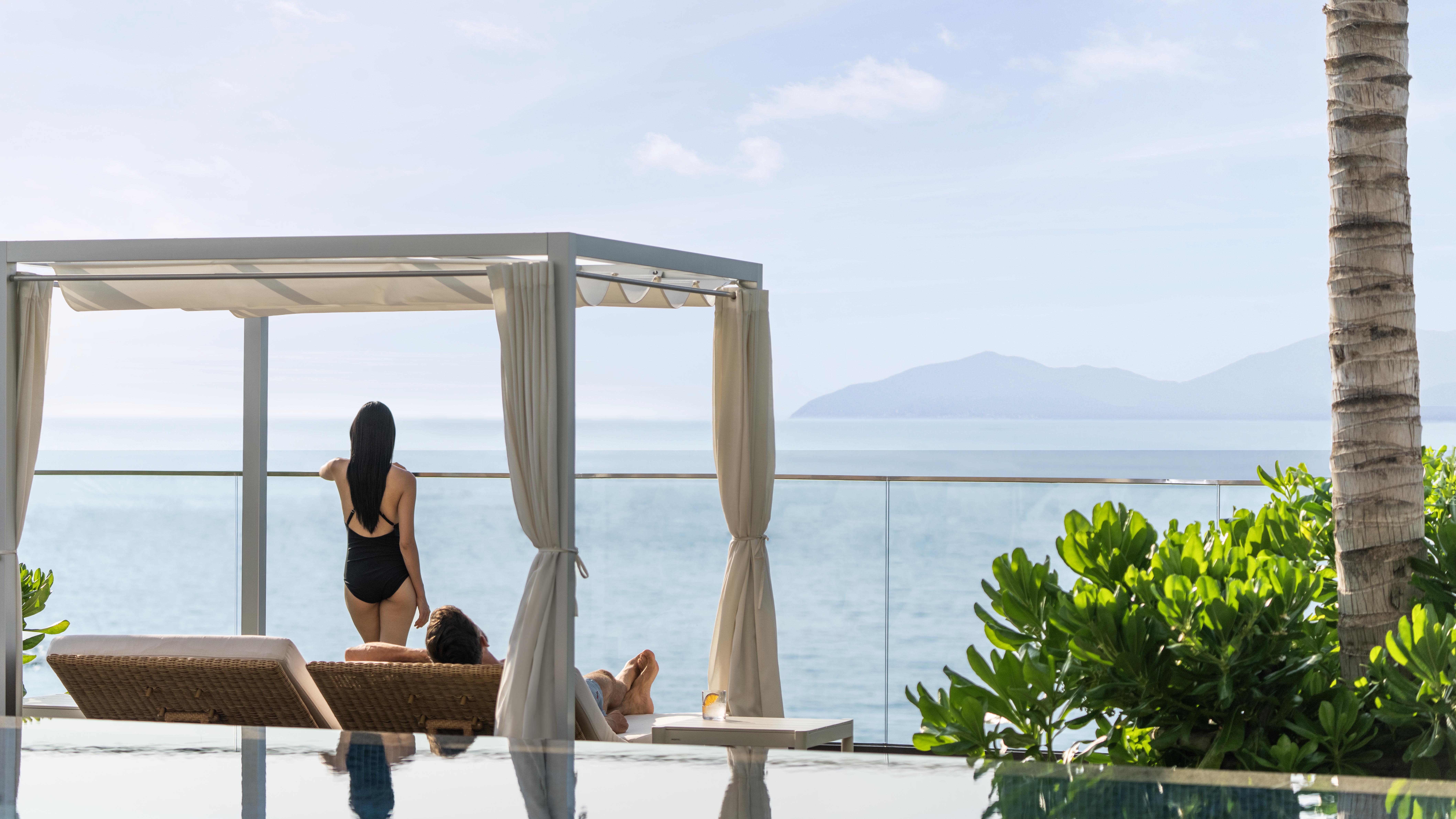 a woman in a swimsuit on a deck overlooking a body of water