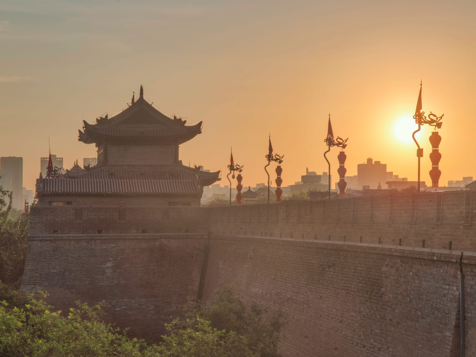 a wall with a building and a tower with a sunset