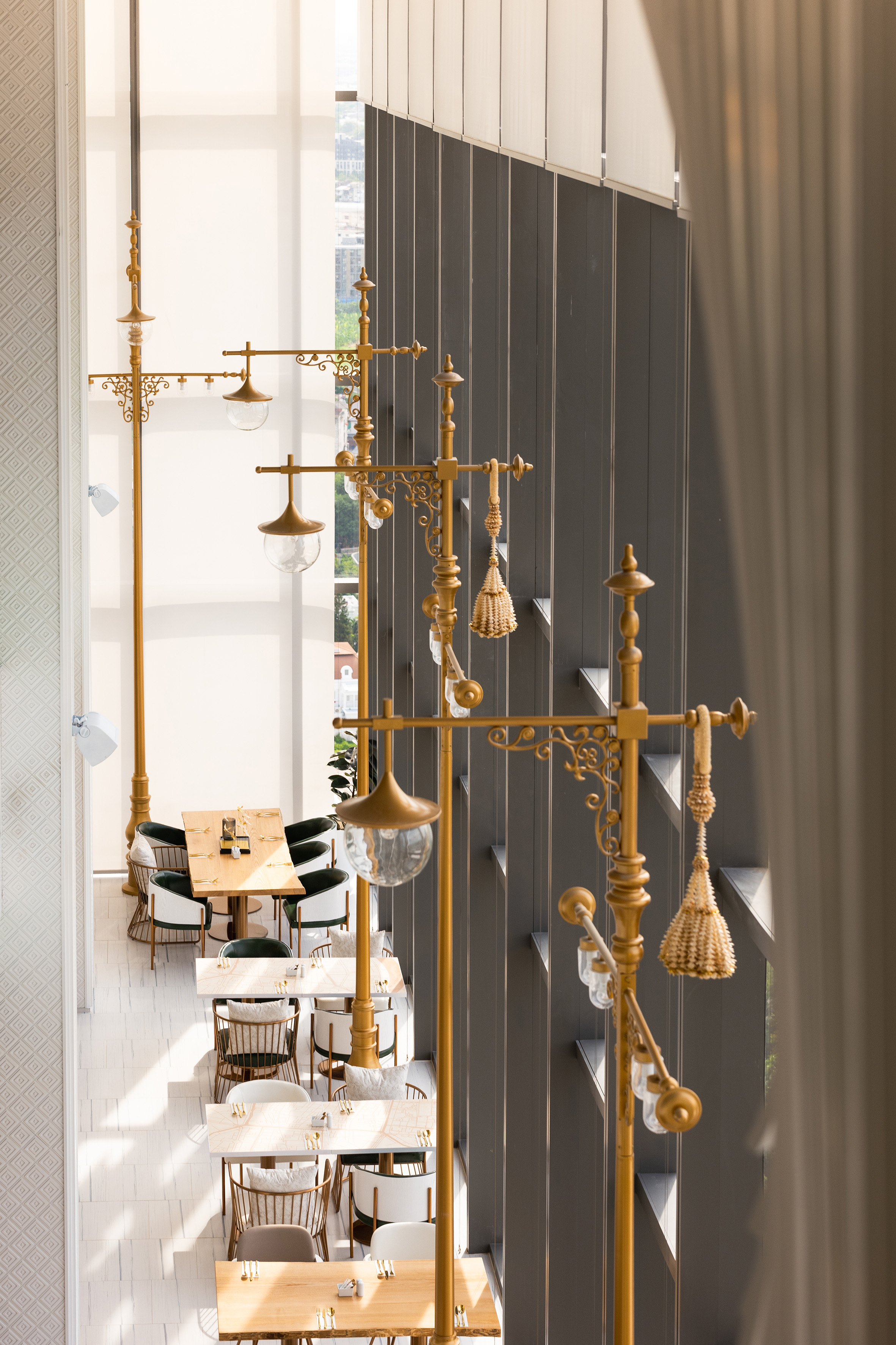 Gold ornate lights illuminate an elegant restaurant dining room with stylish tables.
