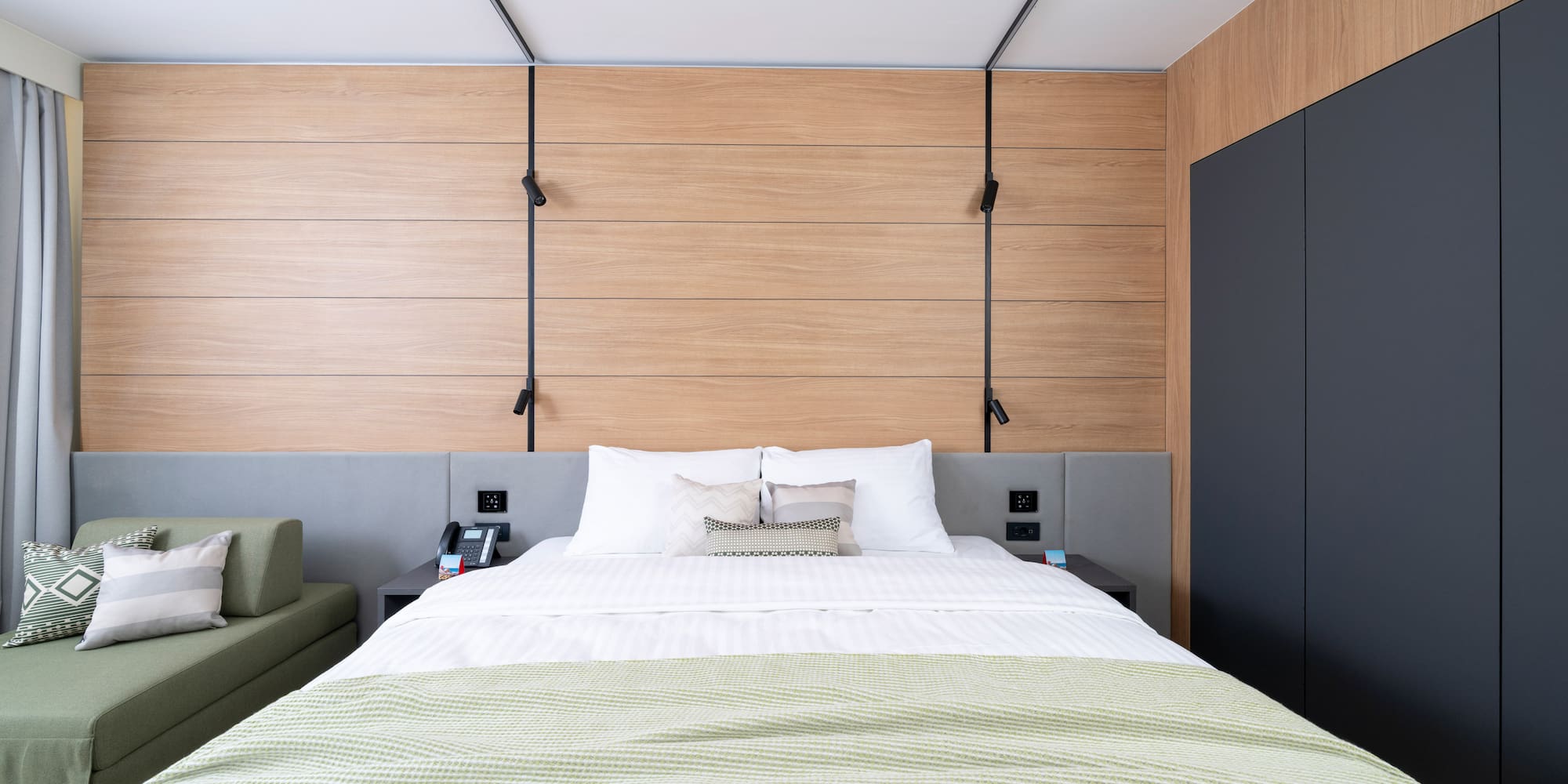 a bed with a green blanket and a black cabinet