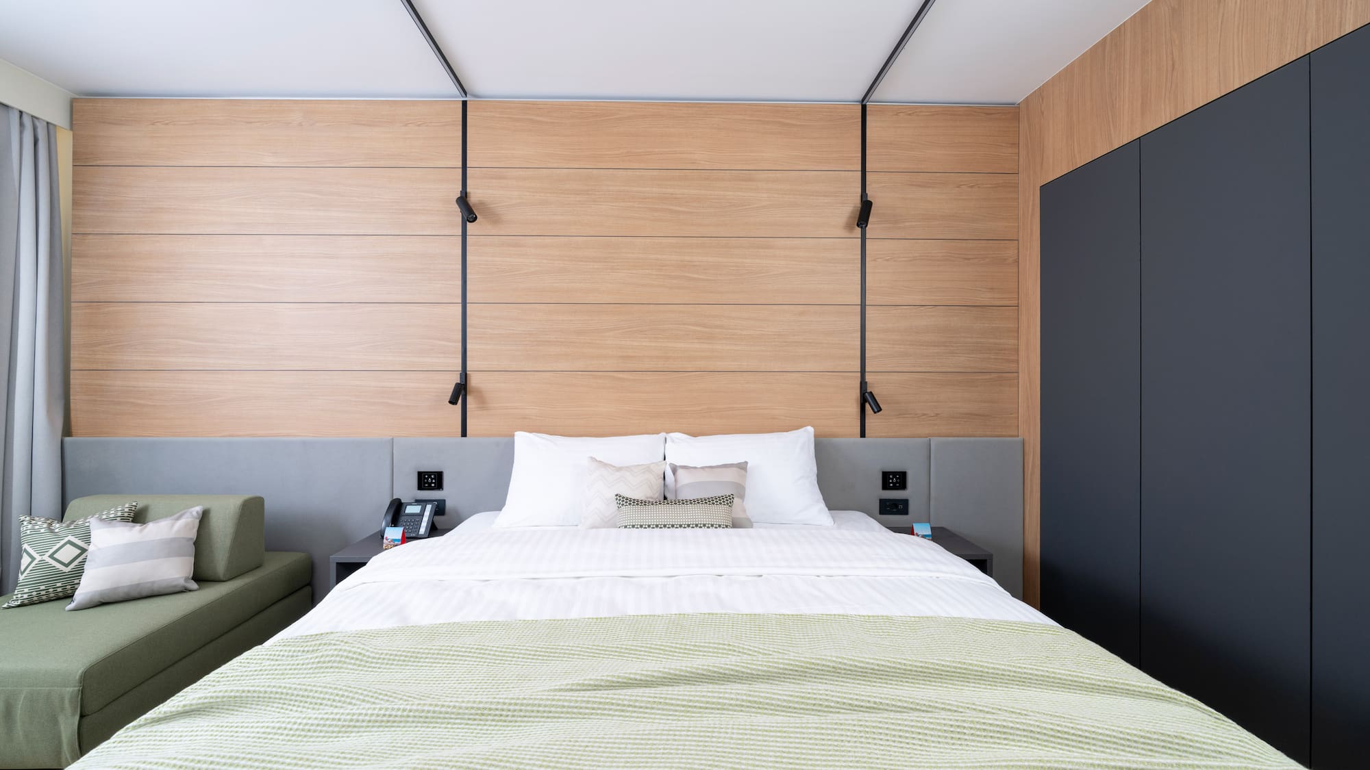 a bed with a green blanket and a black cabinet